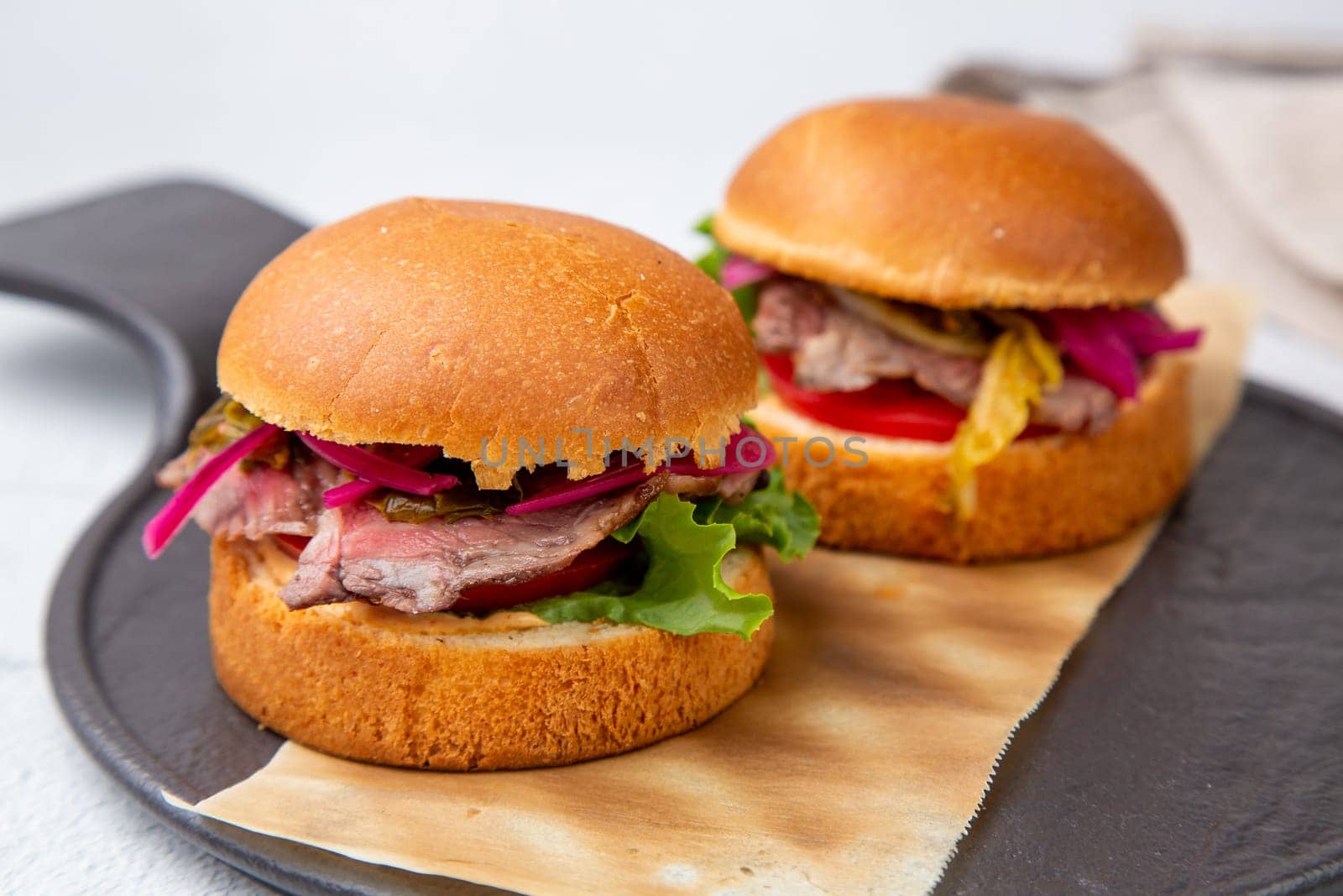 hot burgers with lettuce and vegetables on a wooden board