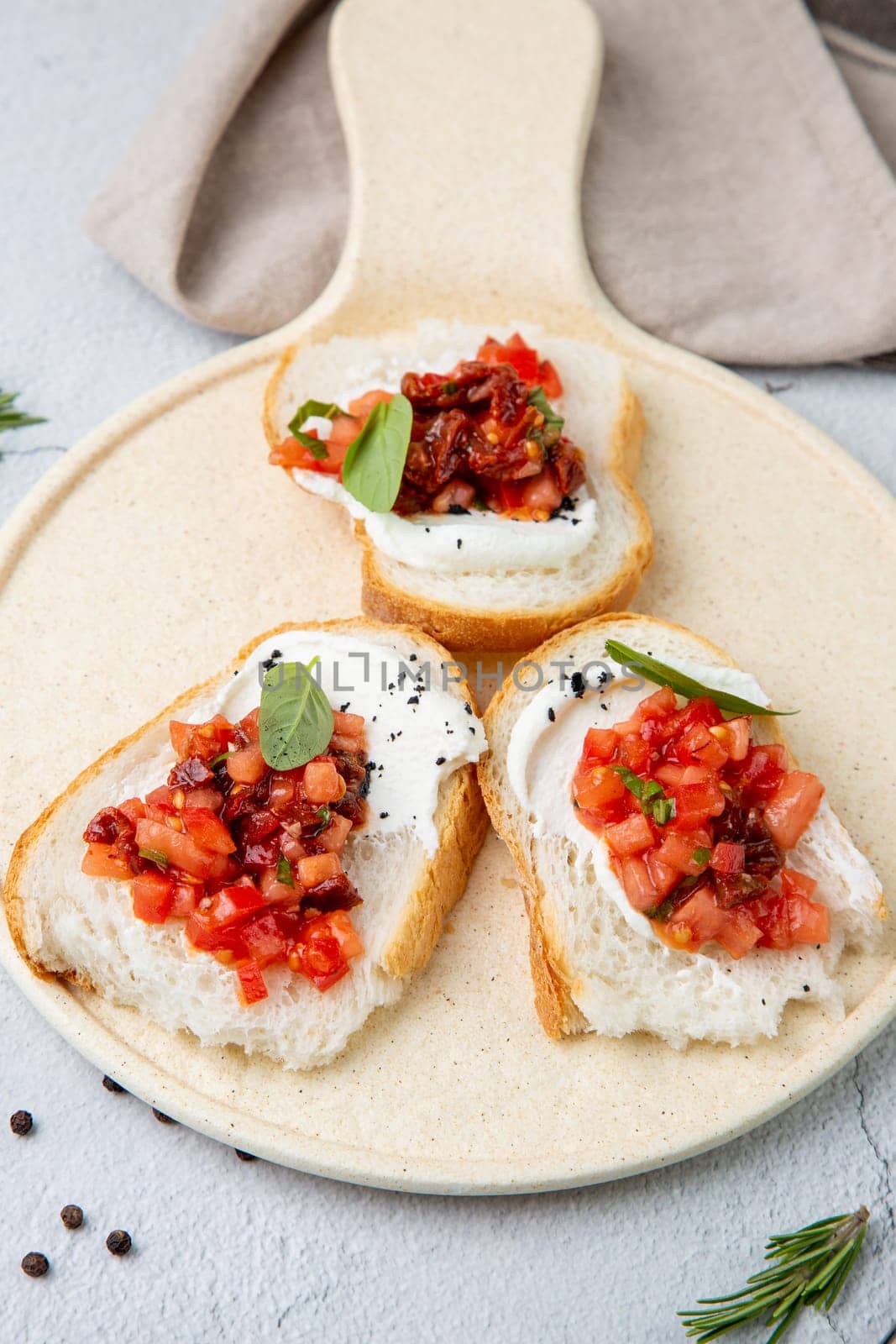 bruschetta with tomatoes and labneh cheese on a light background side view by tewolf