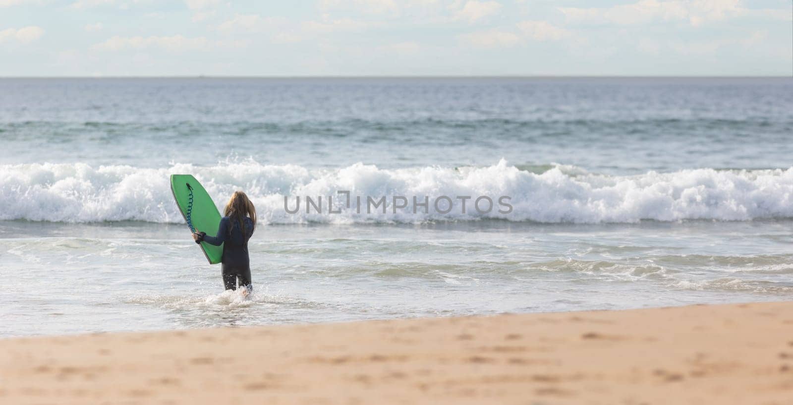 Teen girl holding a surf board in the ocean