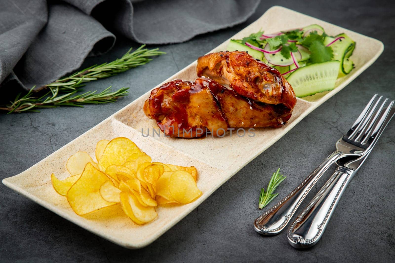 European dish. Chicken in sauce, with fried potatoes and cucumber salad, herbs and onions. dark background