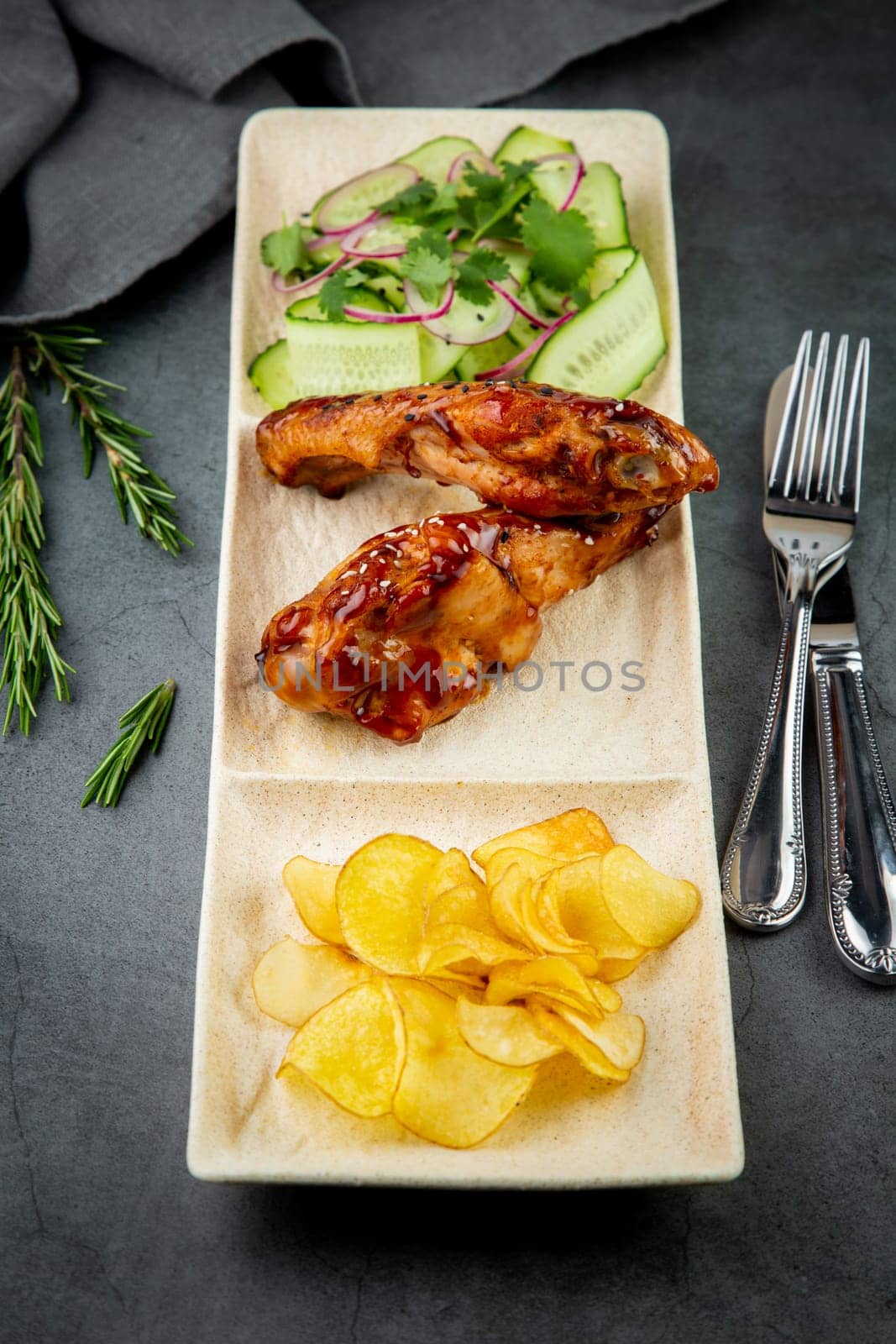 European dish. Chicken in sauce, with fried potatoes and cucumber salad, herbs and onions. dark background