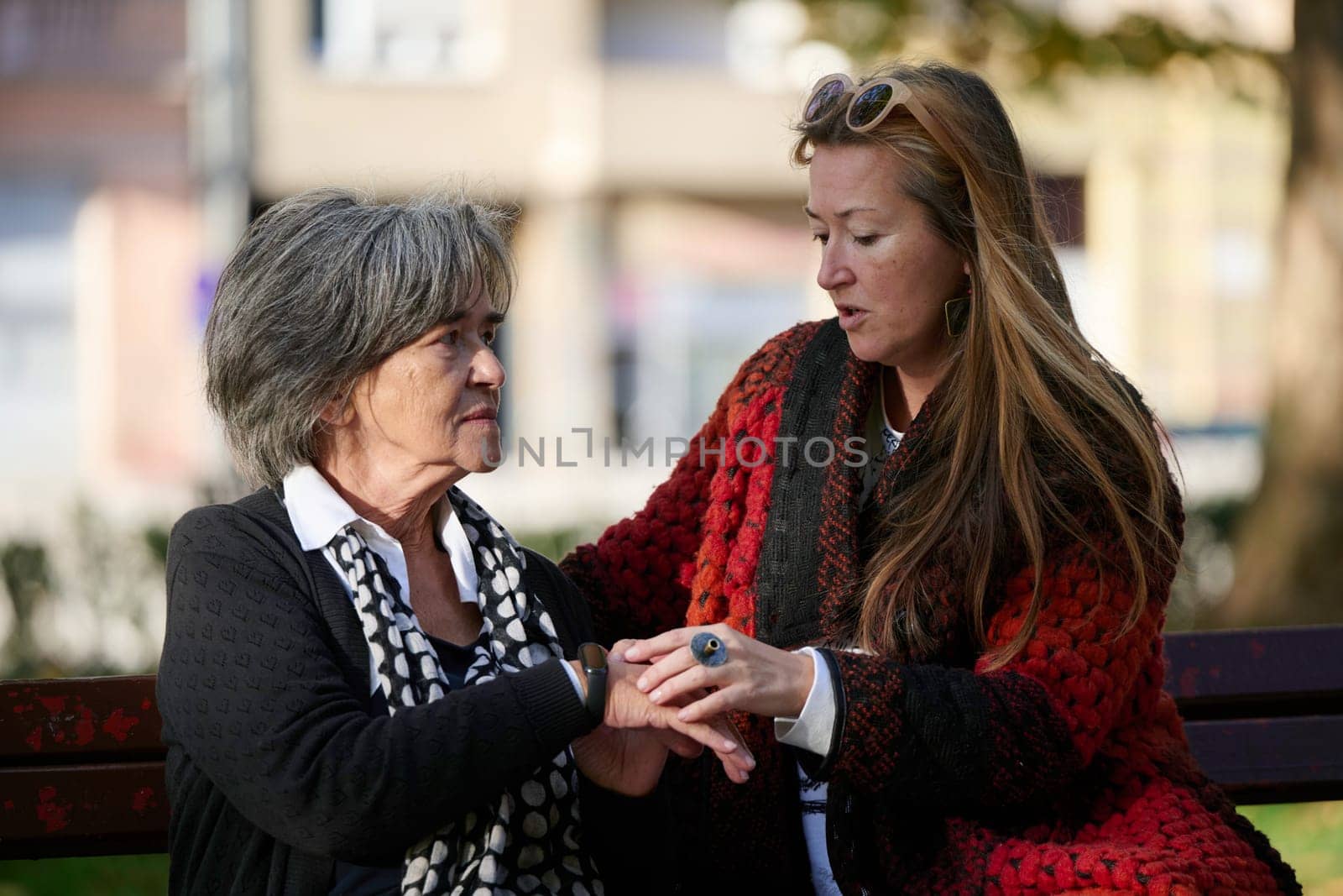 Elderly old cute woman with Alzheimer's very happy and smiling when eldest daughter hugs and takes care of her in park in autumn. Theme aging and parenting, family relationships and social care.