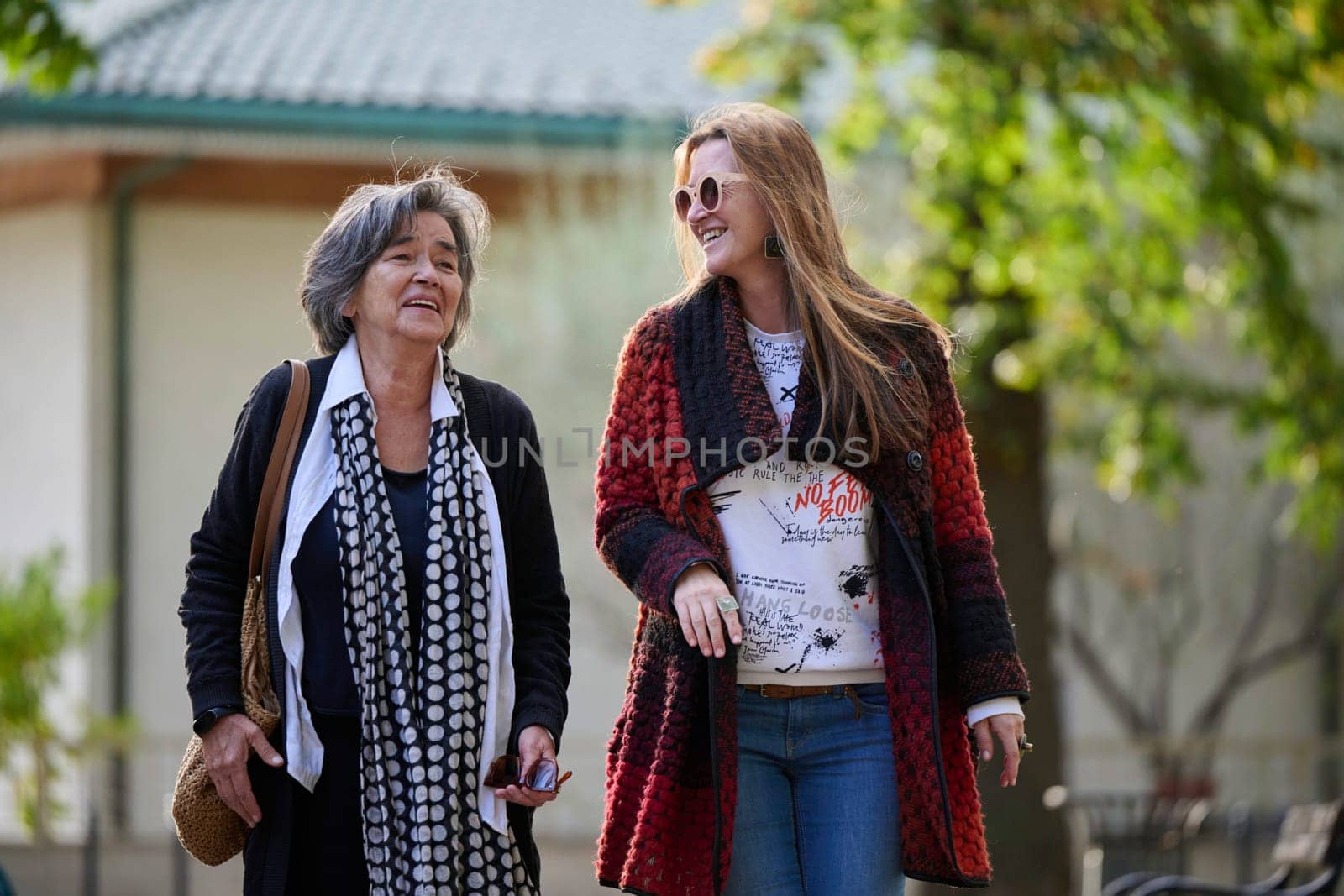 Elderly old cute woman with Alzheimer's very happy and smiling when eldest daughter hugs and takes care of her in park in autumn. Theme aging and parenting, family relationships and social care.