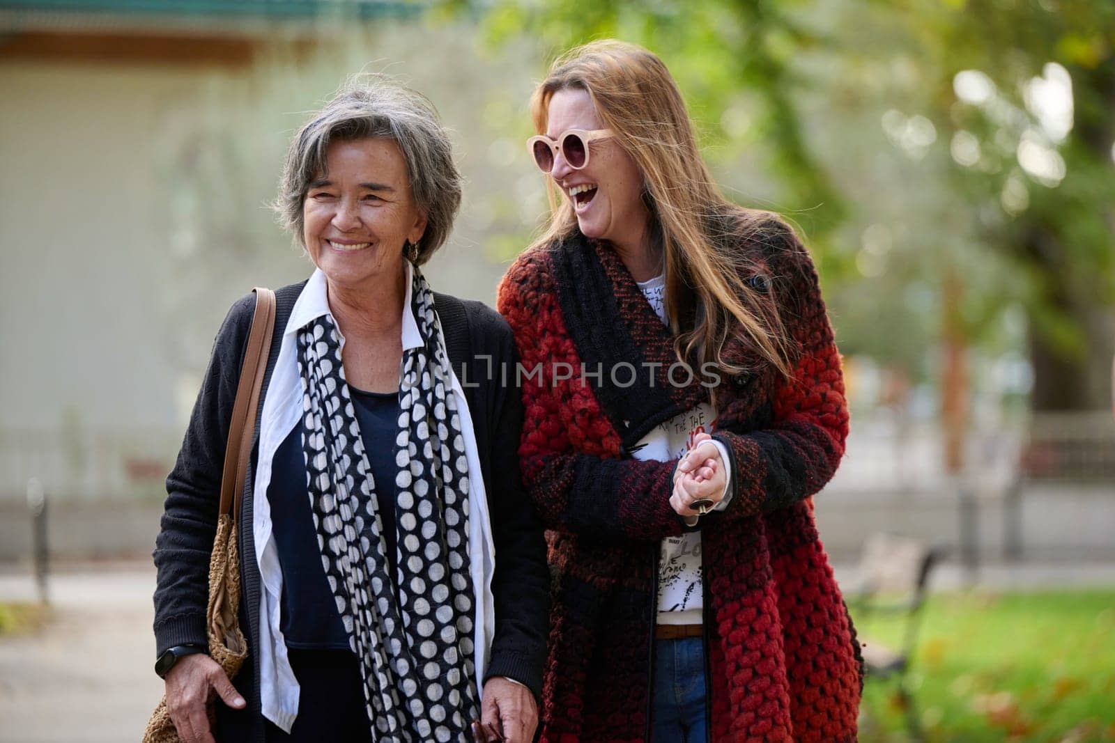 Elderly old cute woman with Alzheimer's very happy and smiling when eldest daughter hugs and takes care of her in park in autumn. Theme aging and parenting, family relationships and social care.