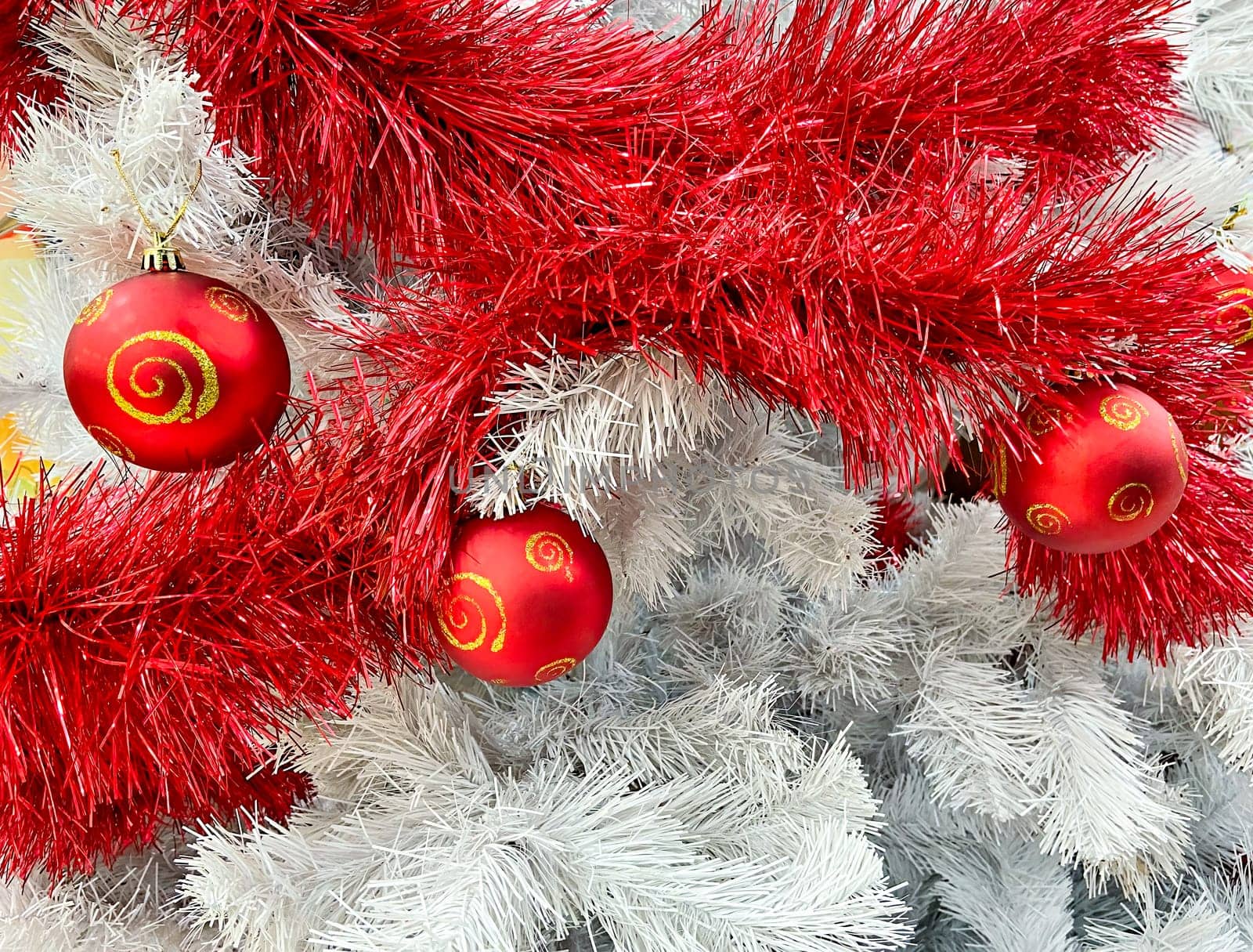 Red baubles with golden ornament on white pine tree brenches. Closeup look of Christmas decorations