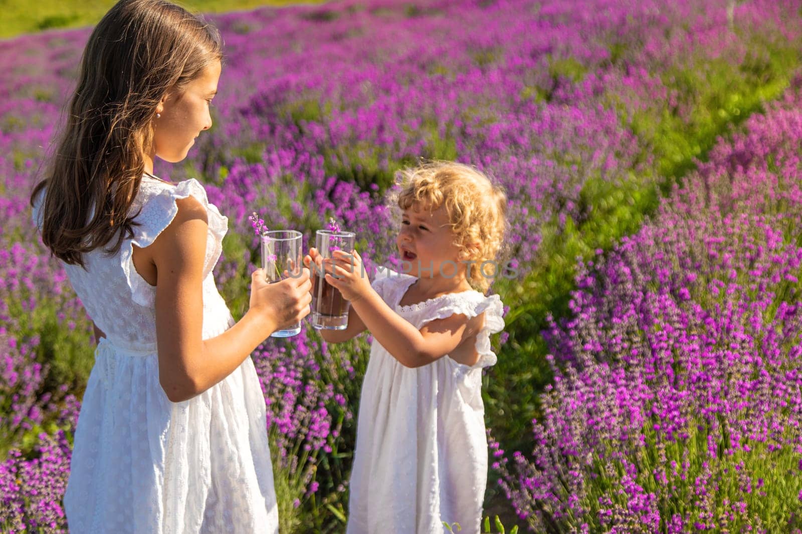 Children in a lavender field drink lemonade. Selective focus. by yanadjana