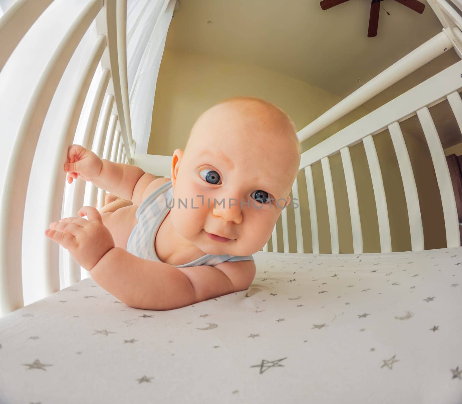 A playful baby in the crib, gleefully staring at the camera, radiating joy.