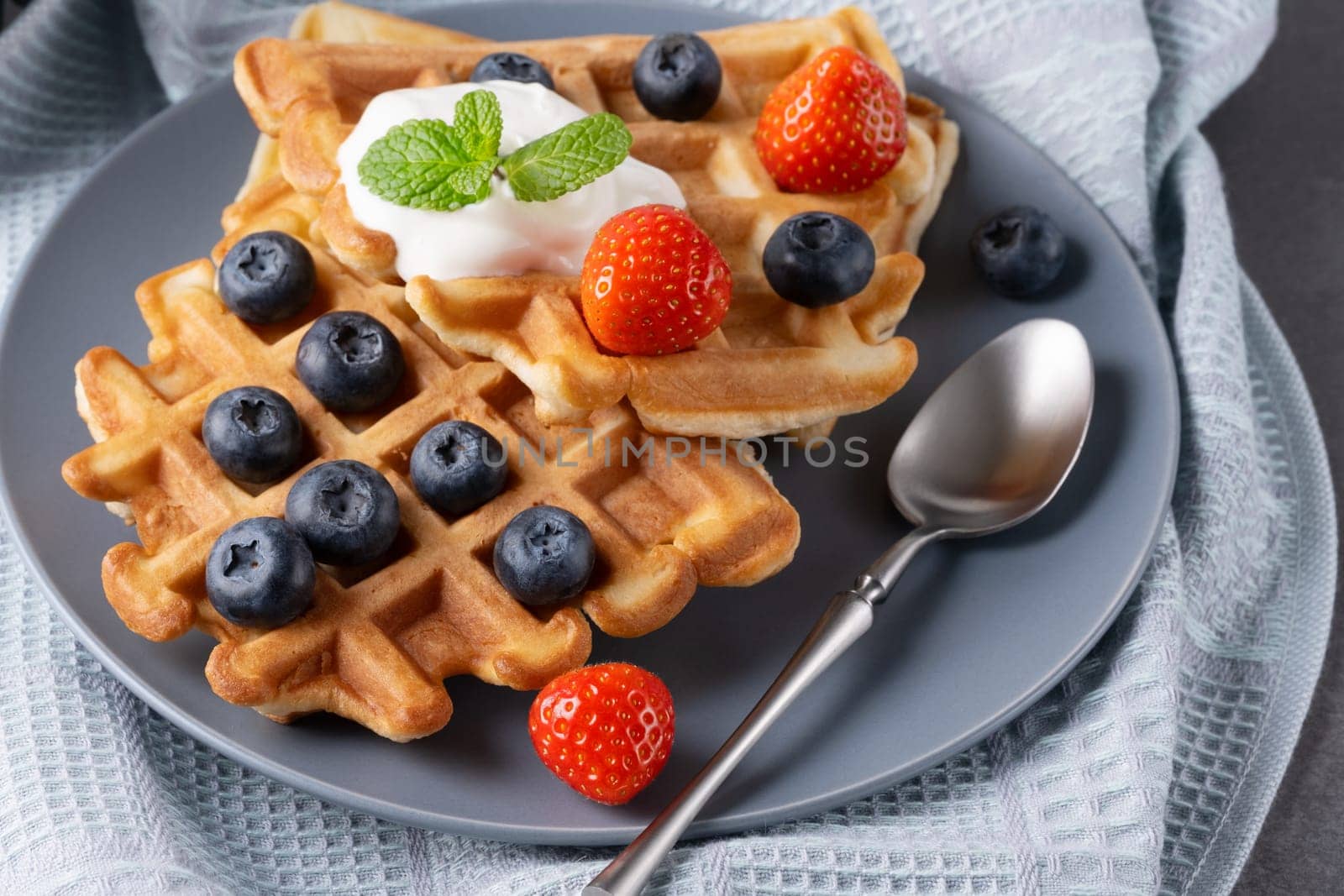 Delicious waffles with whipped cream, strawberries and blueberries.
