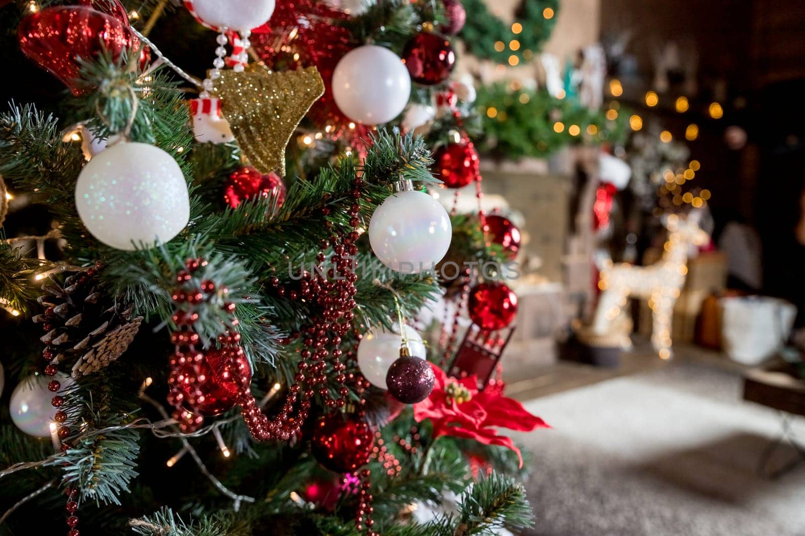 Christmas, New Year interior with red brick wall background, decorated fir tree with garlands and balls, dark drawer and deer figure