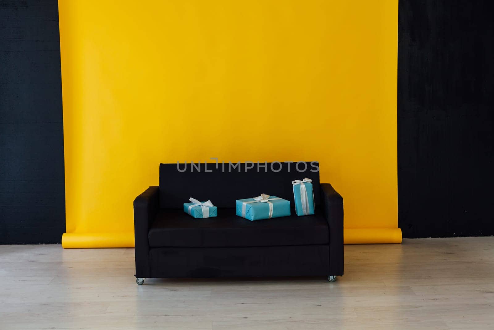 black sofa with gifts in the interior of the yellow room by Simakov