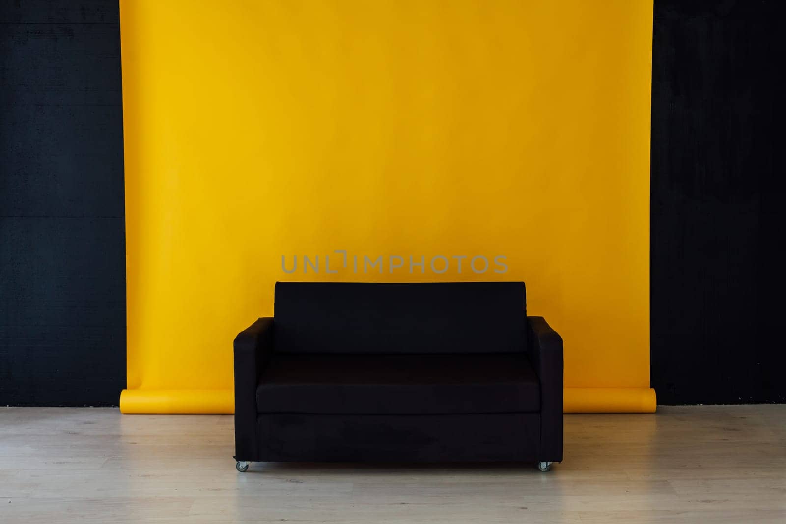 black sofa in the interior of the yellow room by Simakov