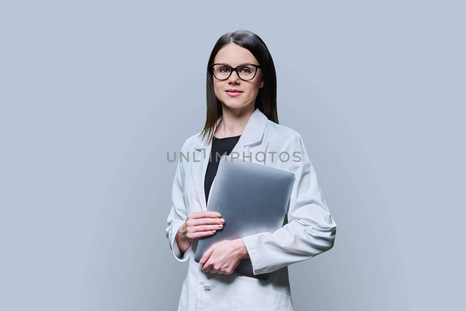 Woman medical scientist, pharmacist in white coat with laptop on grey background by VH-studio