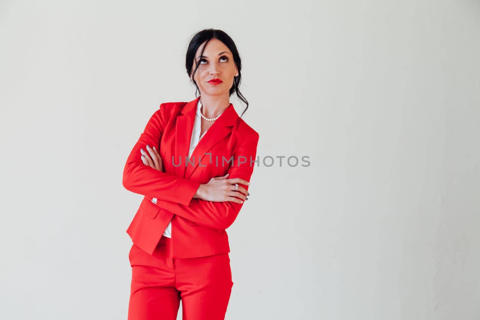 Portrait of a brunette woman in a red business suit in a white room by Simakov