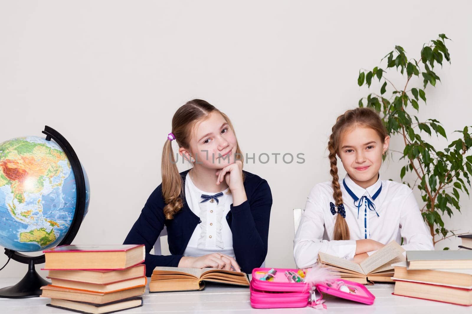 two girls at the desk with books at school by Simakov