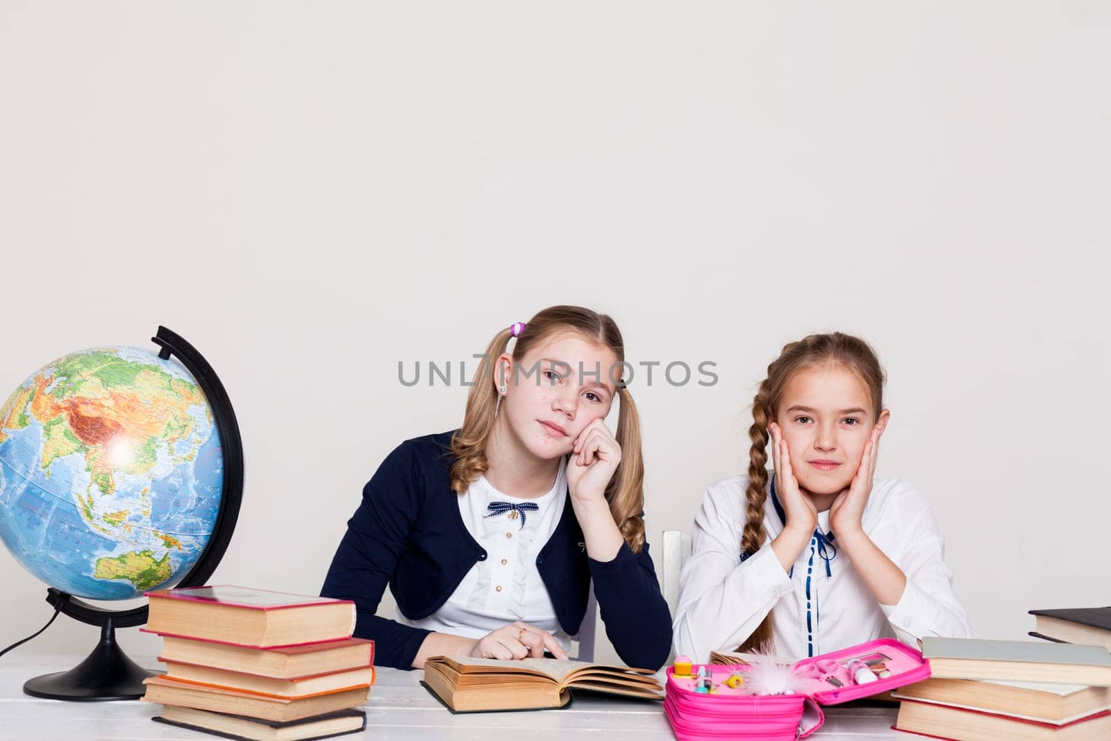 two girls at the desk with books at school by Simakov