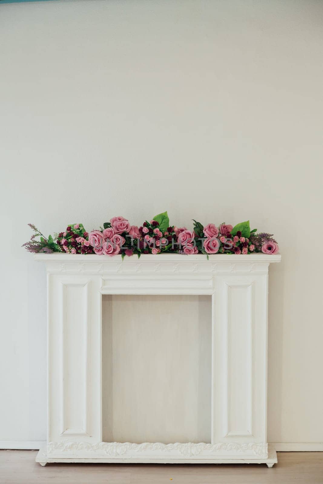 white fireplace with pink flowers against the wall in the room