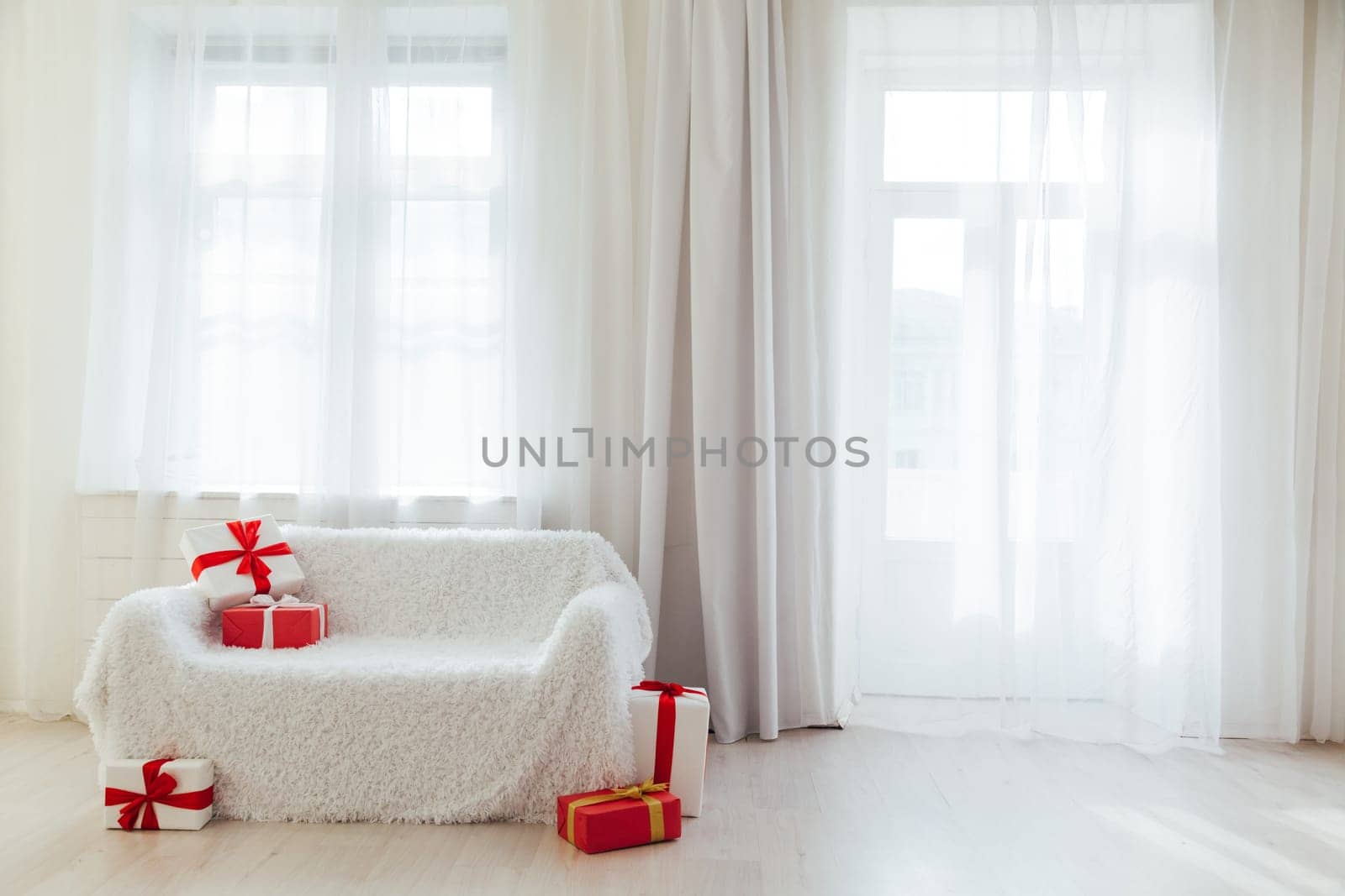 white sofa with birthday gifts in the interior of the white room by Simakov