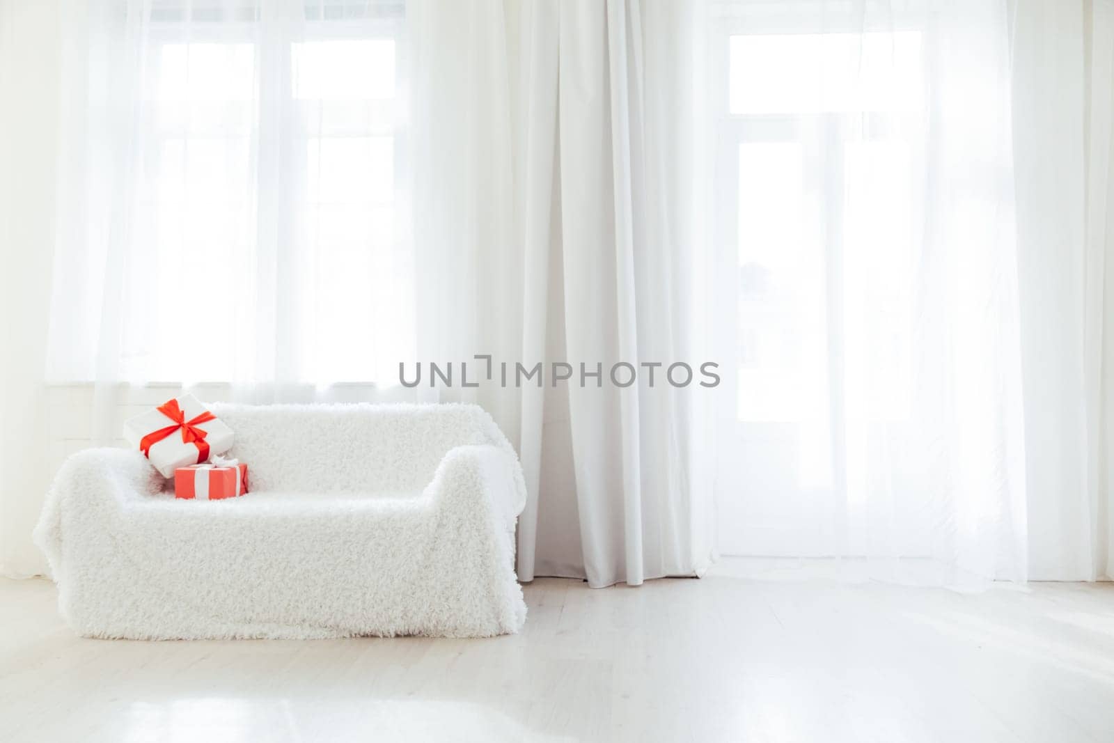 white sofa with gifts in the interior of the white room with a window