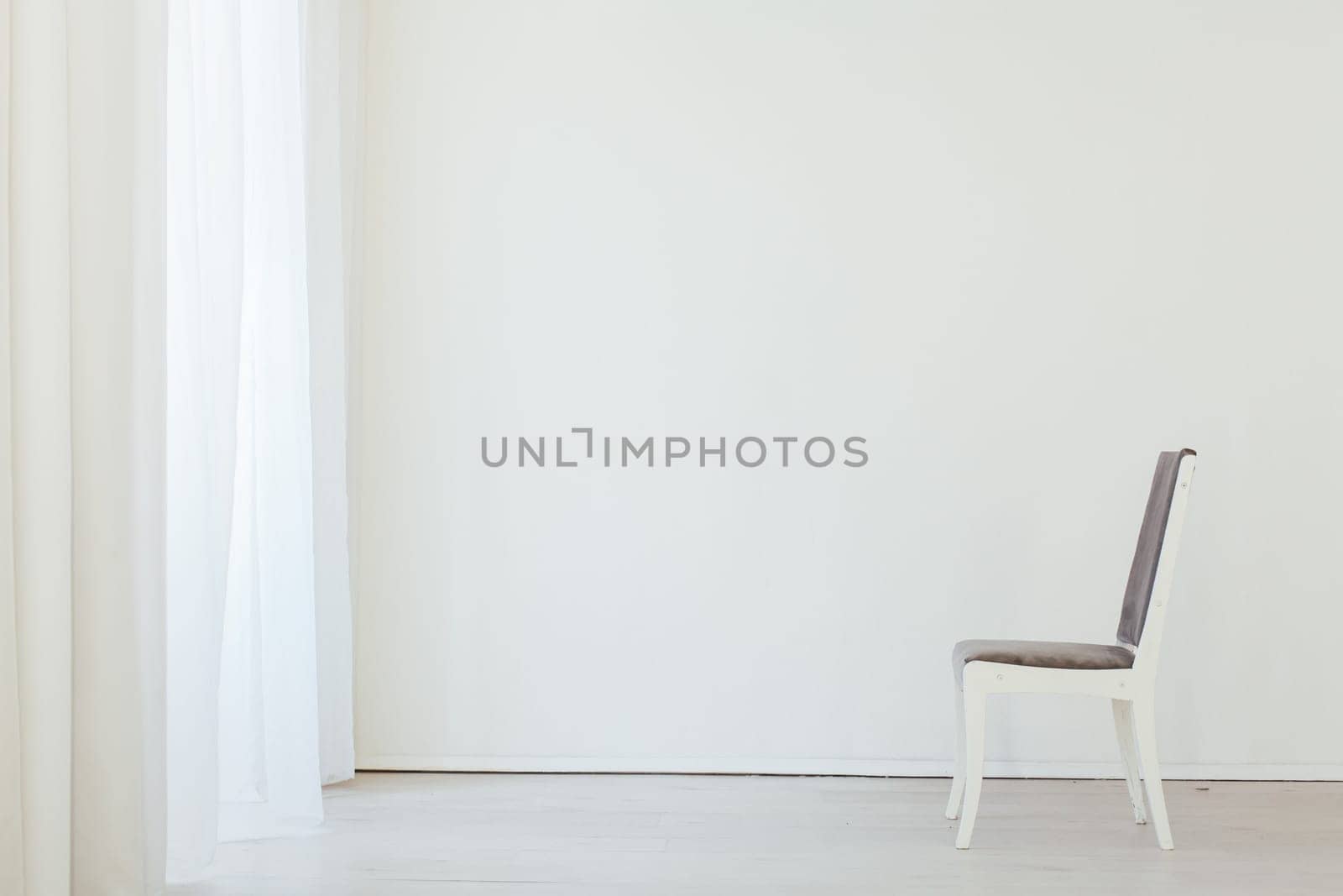 one gray chair in an empty white interior room