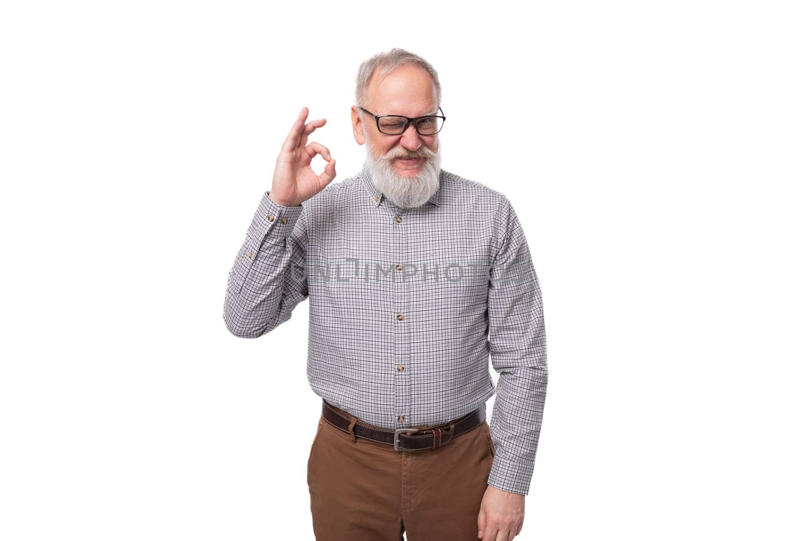 stylish successful grandfather with a white beard and mustache is dressed in a shirt and trousers on a white background with copy space.