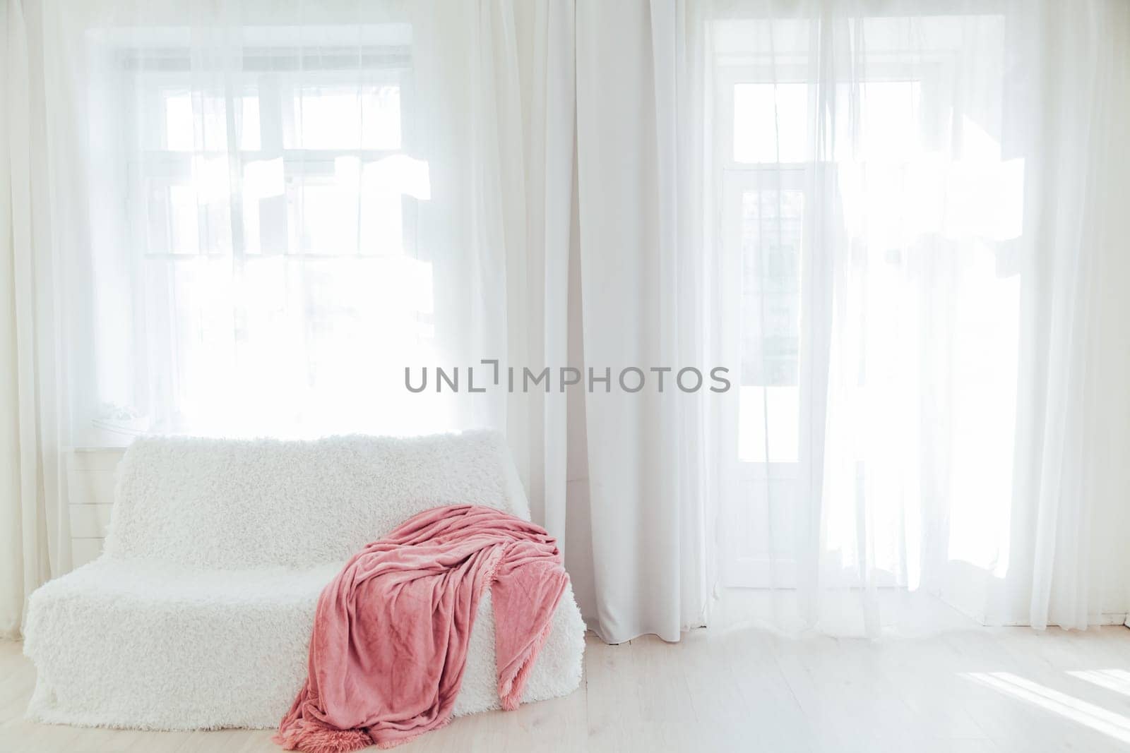 white sofa with pink plaid in the interior of the white room with a window