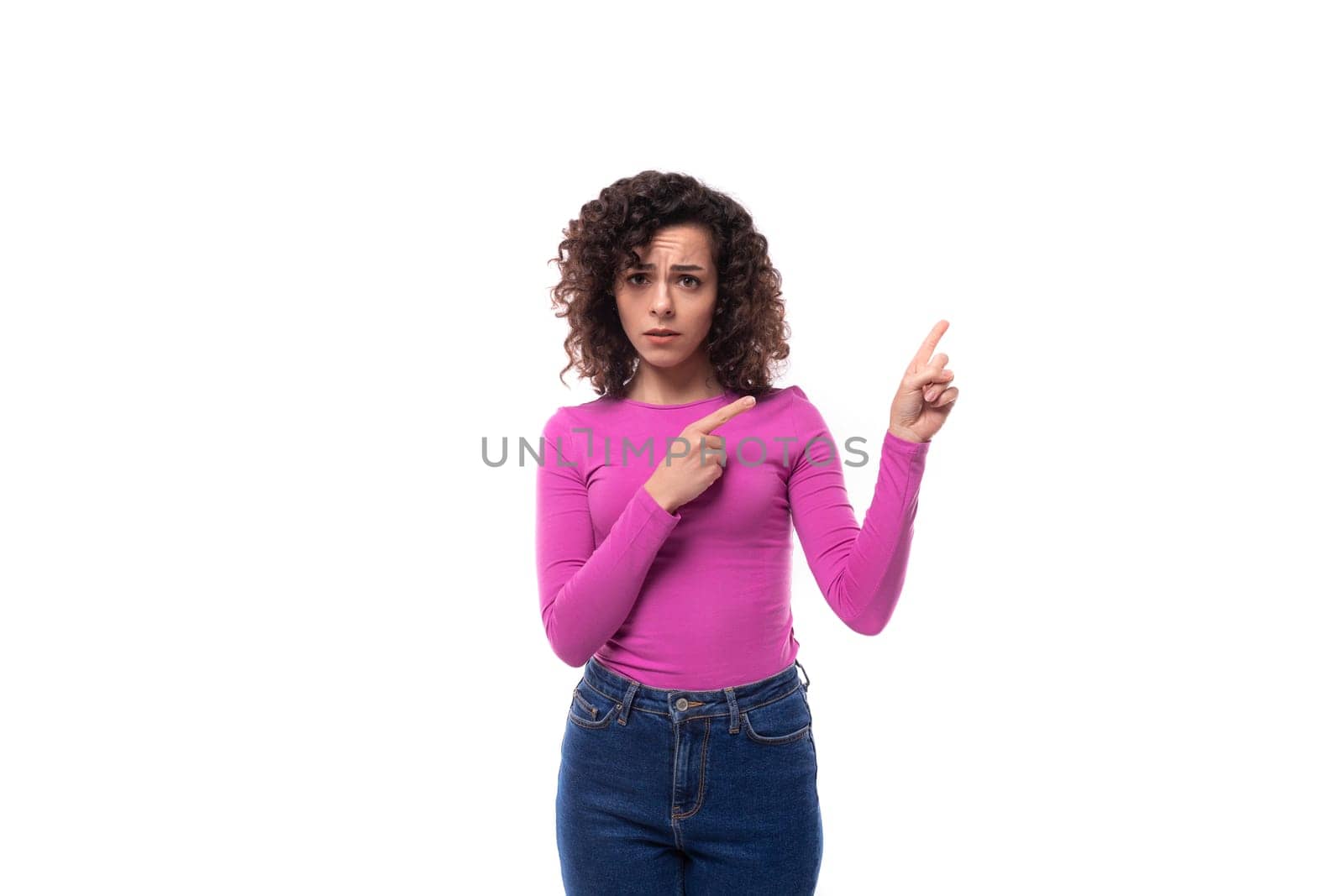 pretty smiling young curly brunette woman dressed in a purple turtleneck points with her hands at the advertisement.