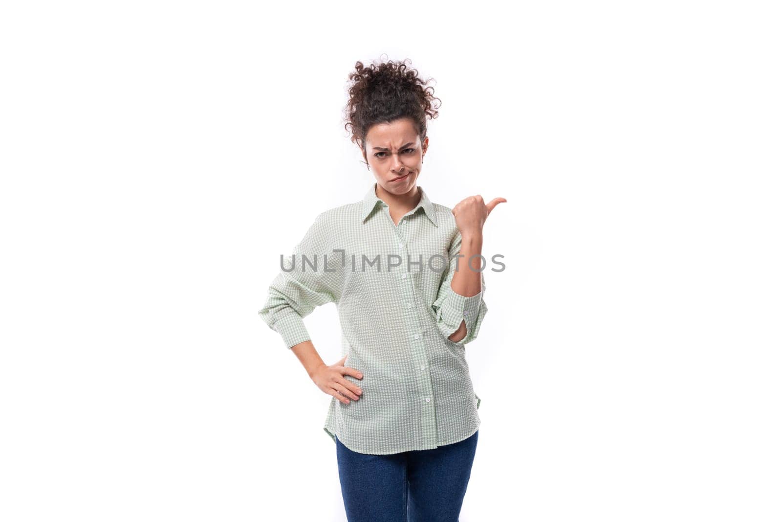a pretty young black-haired curly woman with a careless styling bun in a shirt contemptuously points her hand to the side.