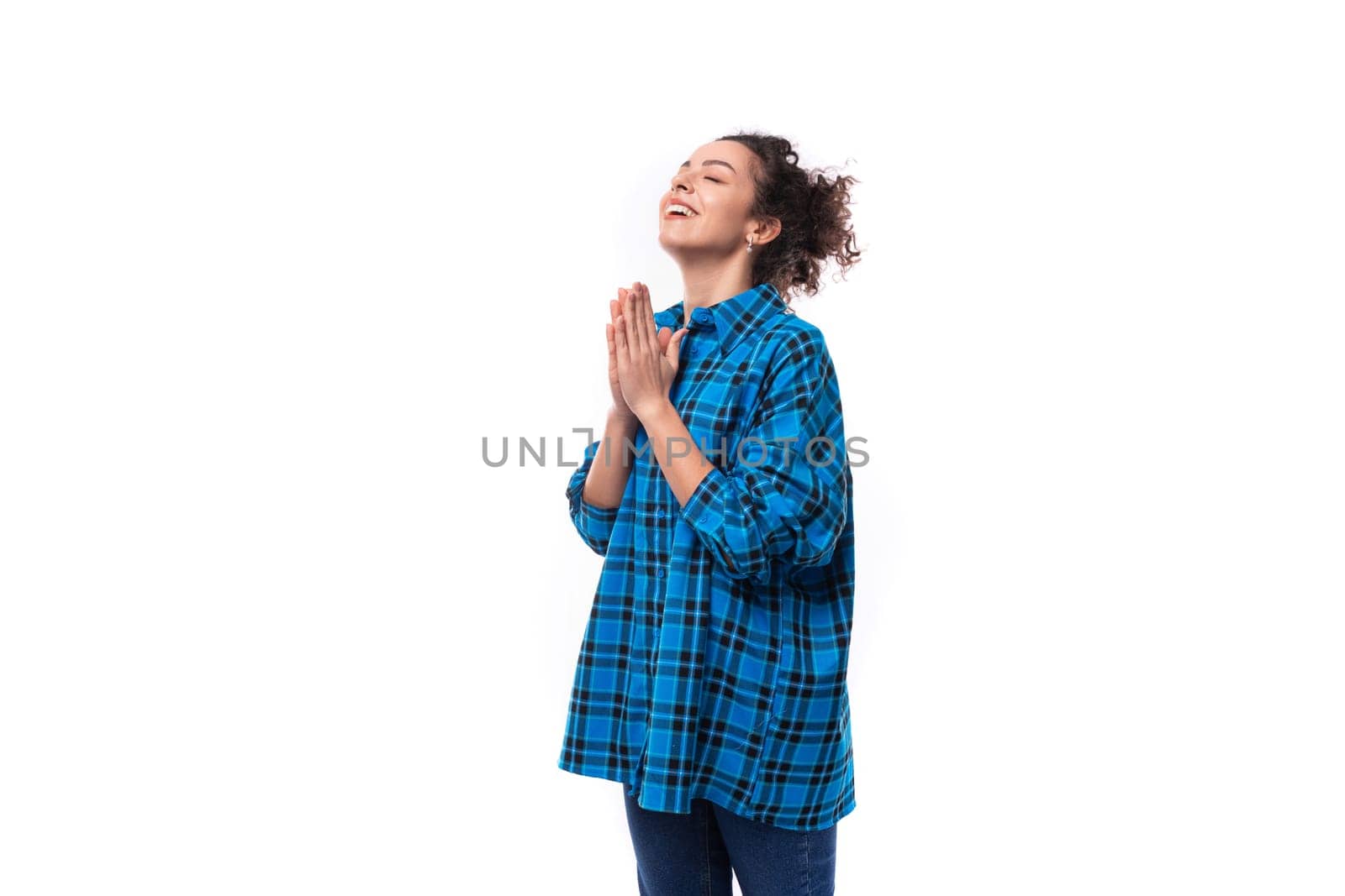 young caucasian brunette woman with her hair gathered in a bun put her hands together for prayer.