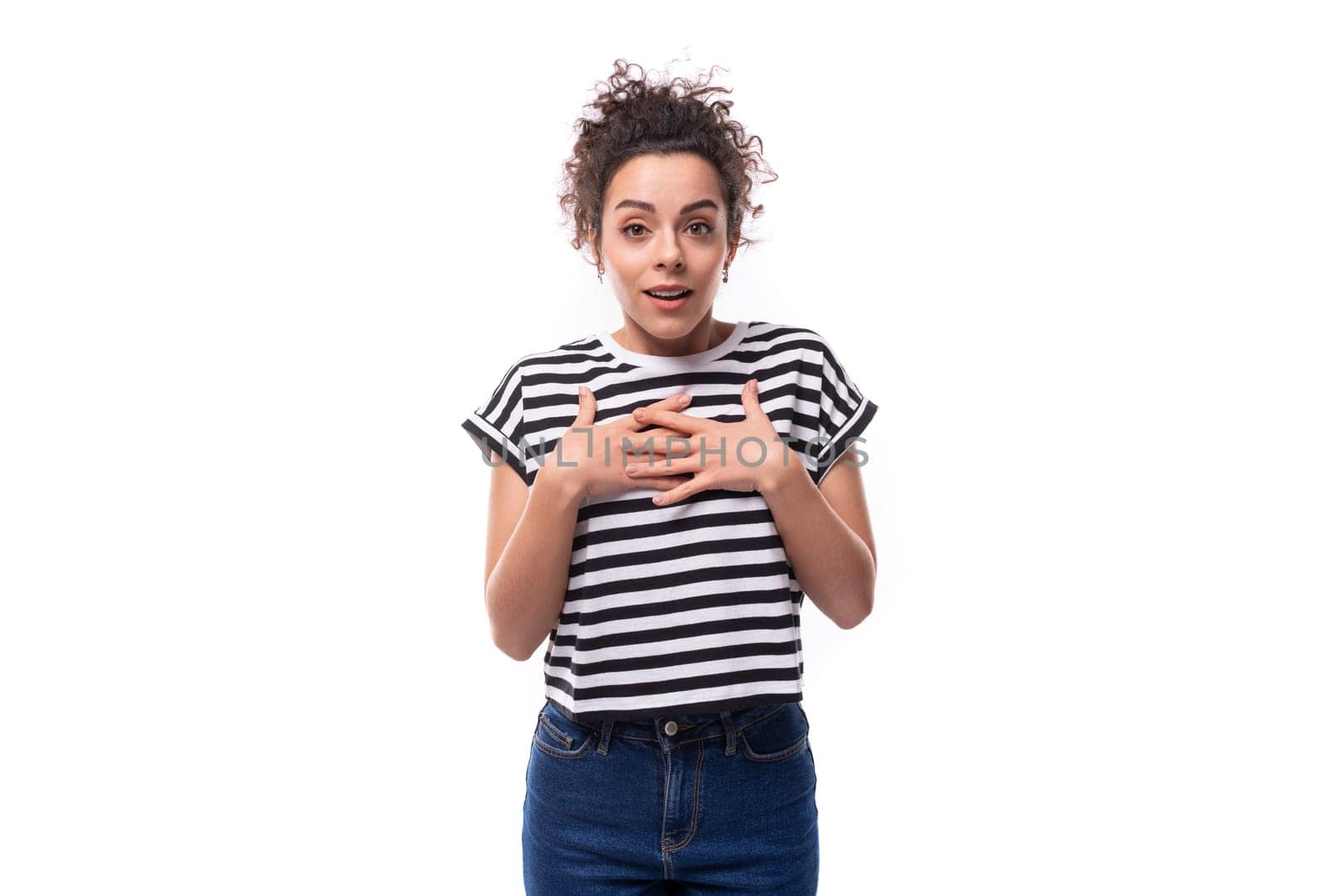 young caucasian woman with curly hair dressed in a striped summer t-shirt looking at the camera in surprise.