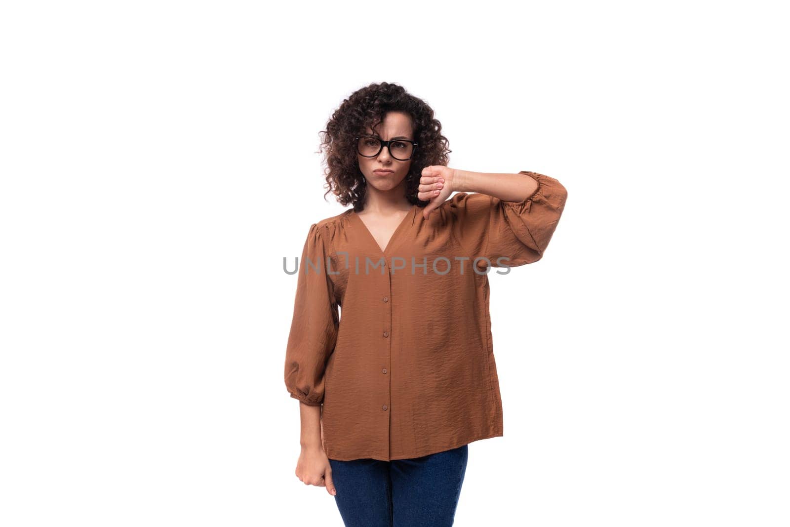 young curly brunette woman dressed in brown blouse shows disagreement gesture by TRMK