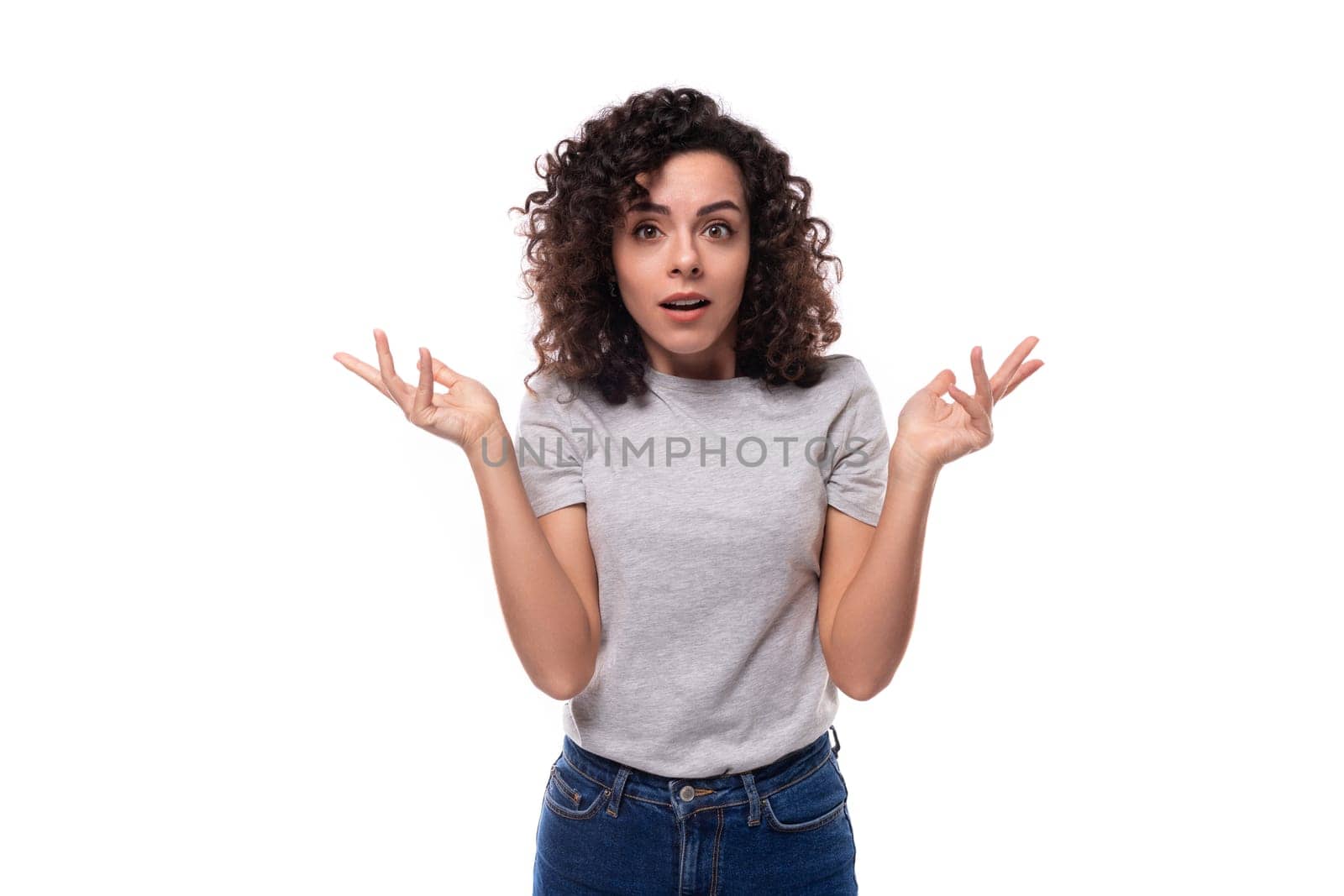 portrait of a cute slim young caucasian woman with careless black curly hair dressed in a gray t-shirt.
