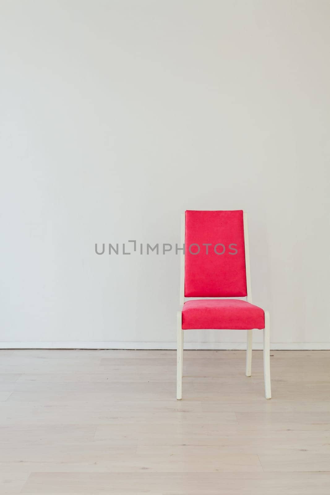 one pink chair in an empty white room