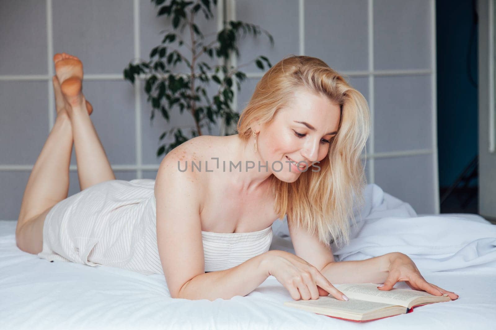 Woman reads a book in the morning in the sleep on the bed