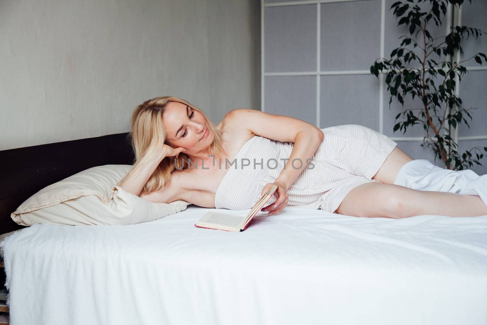 Woman reads a book in the morning in the sleep on the bed