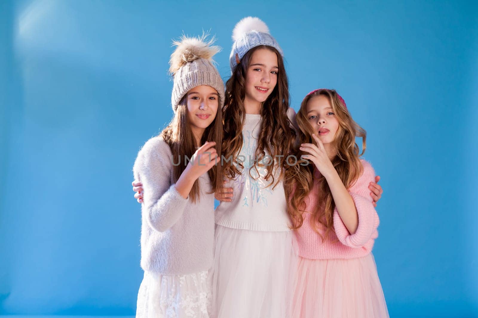 three fashionable beautiful girls in winter hats and warm clothes
