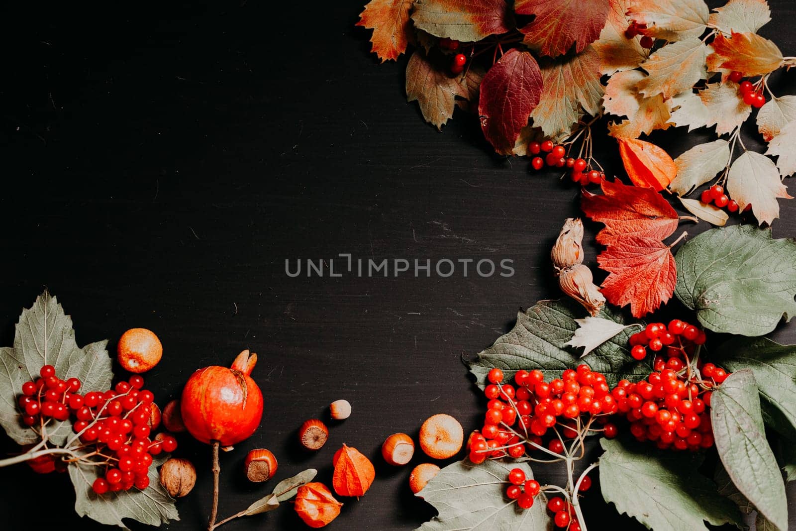 yellow autumn leaves fruit pomegranate nuts on a black background by Simakov