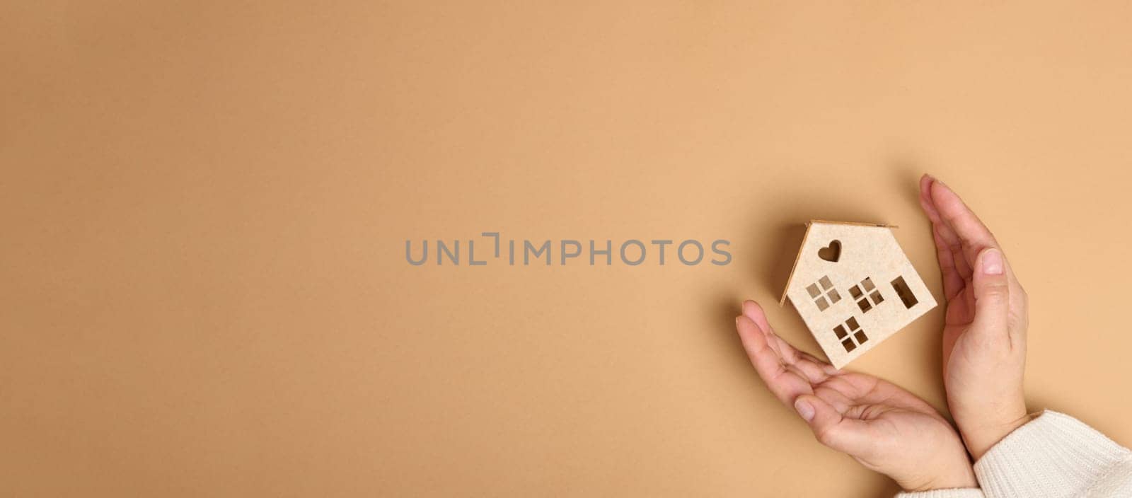 Wooden miniature model house on a brown background. Real estate insurance concept by ndanko