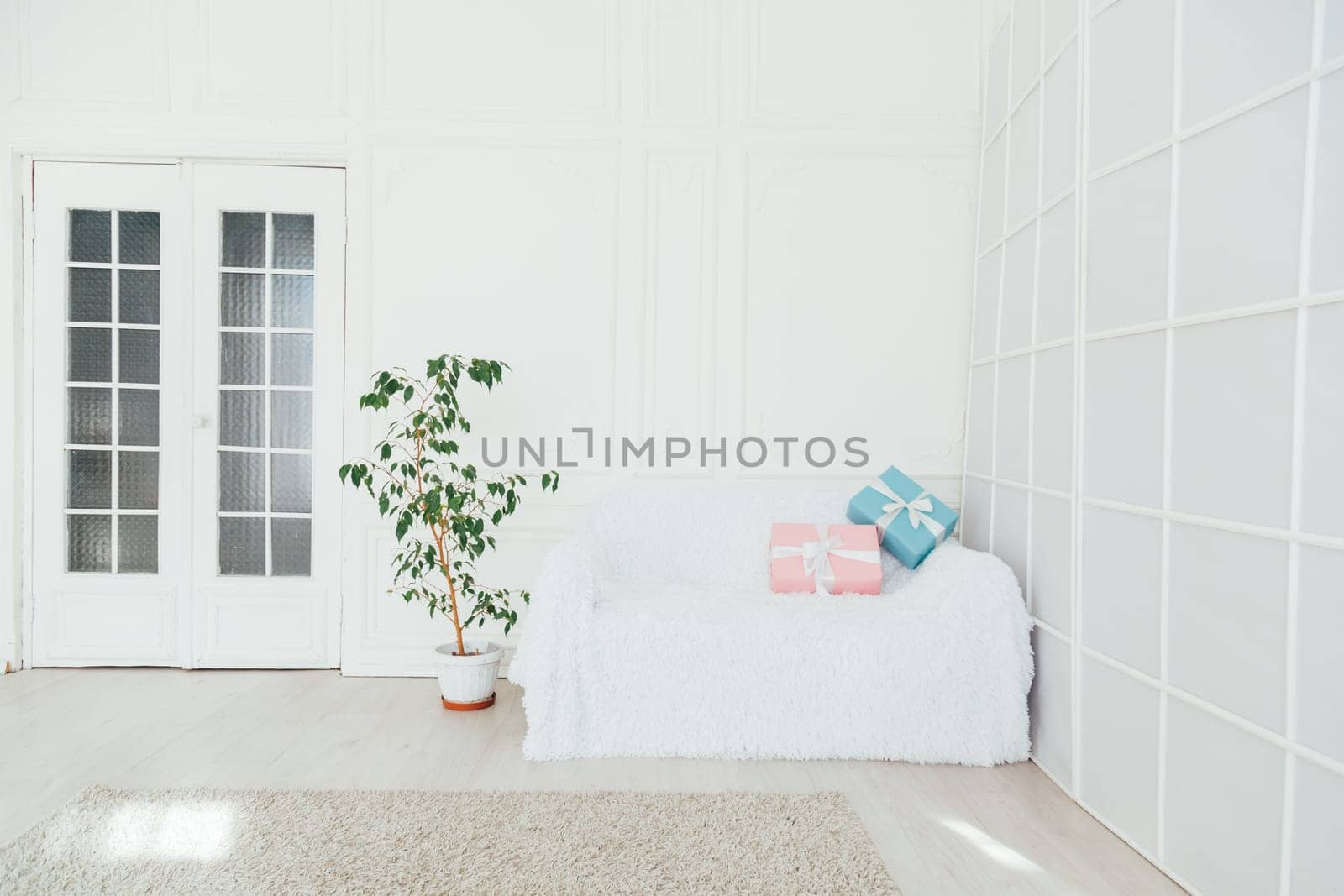 white sofa with gifts in the interior of the white room by Simakov
