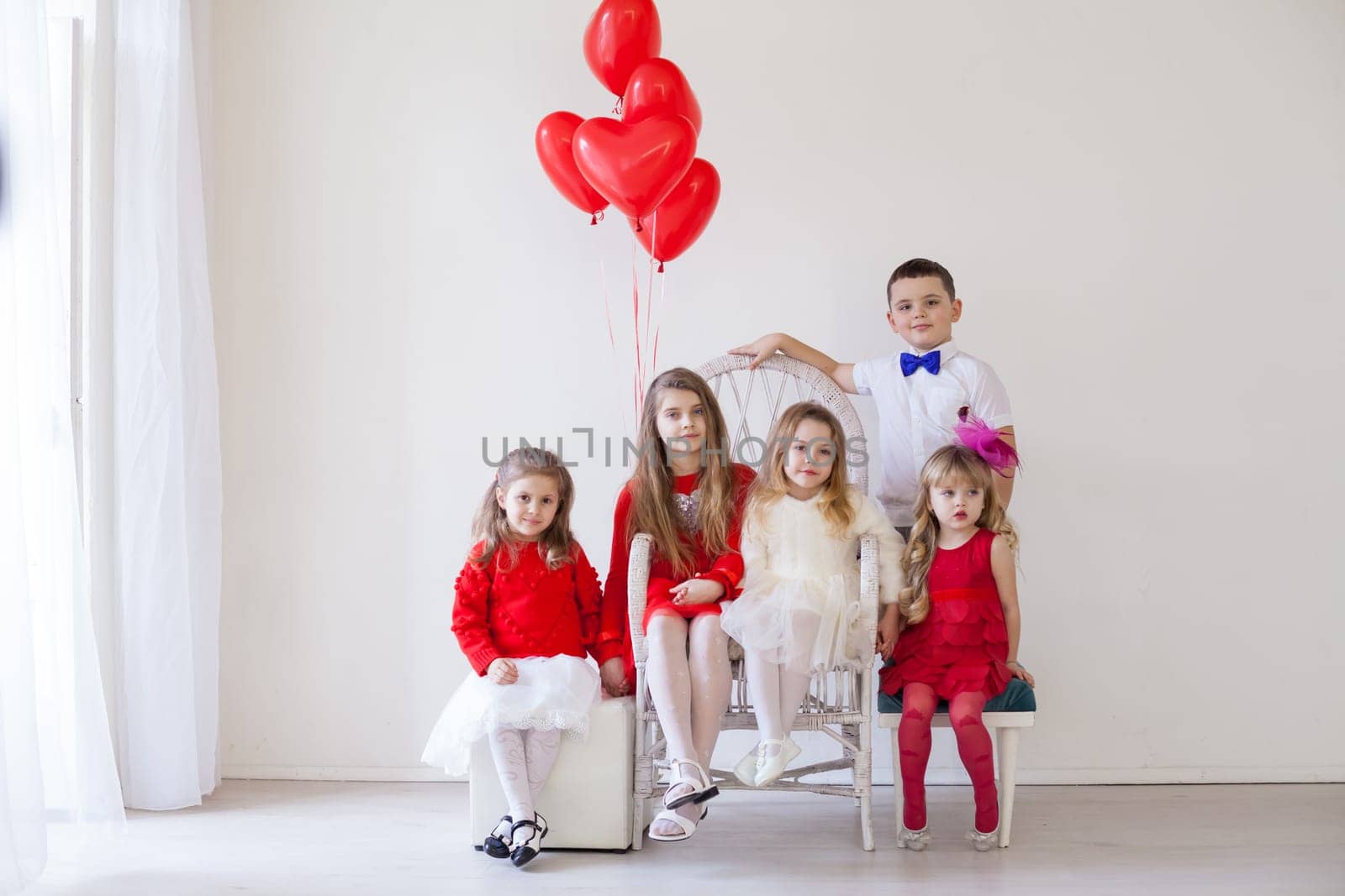 Kids with red balloons for birthday in the interior of the white room