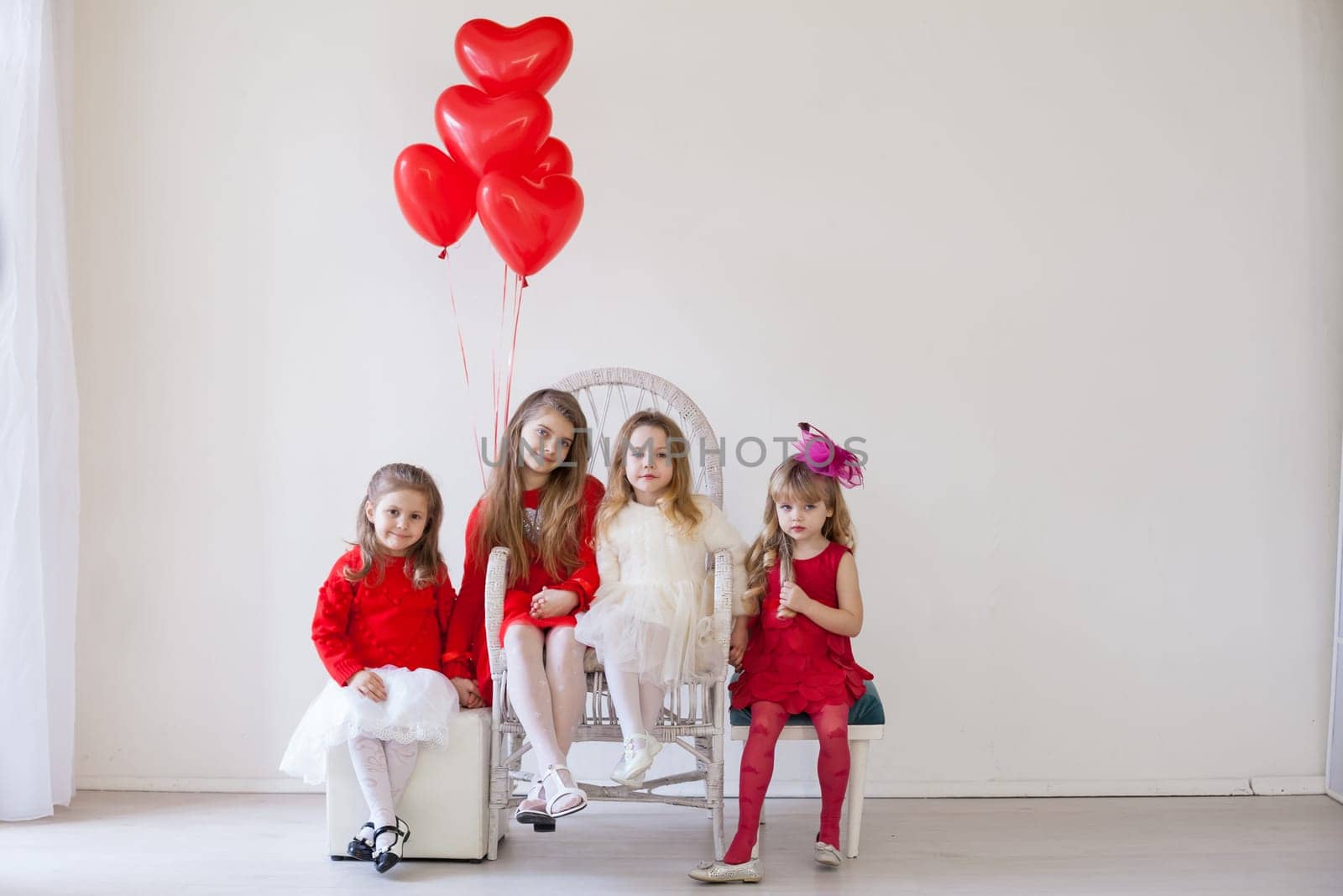 Kids with red balloons for birthday in the interior of the white room