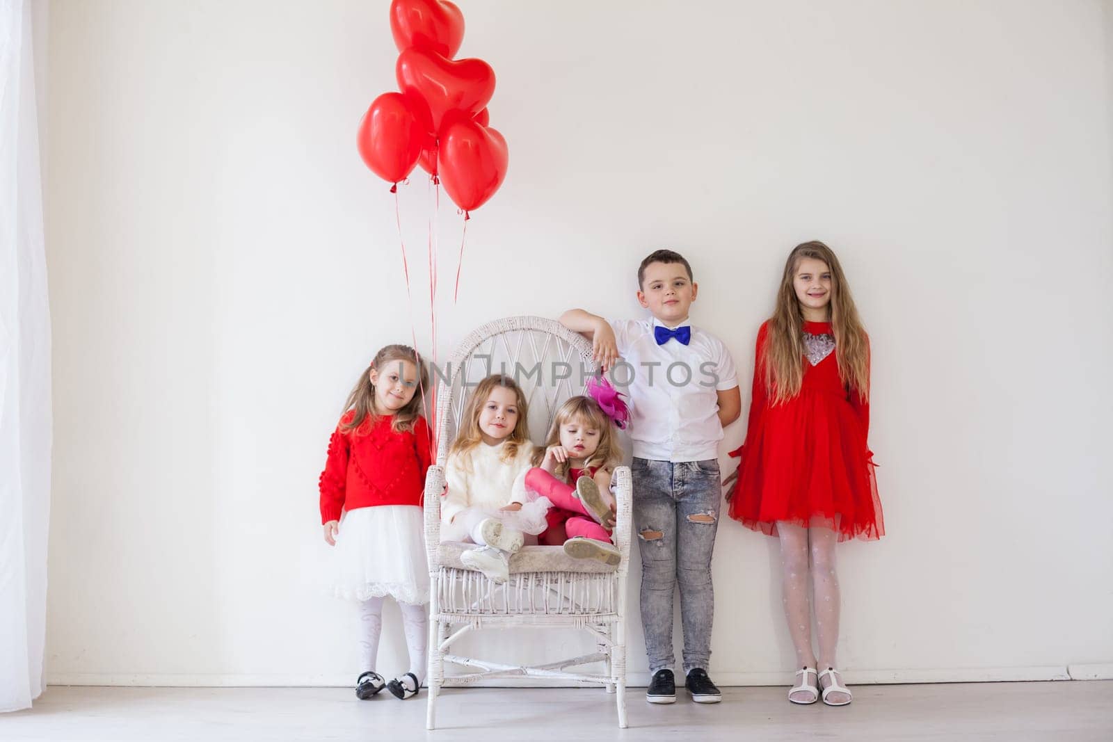 Kids with red balloons for birthday in the interior of the white room