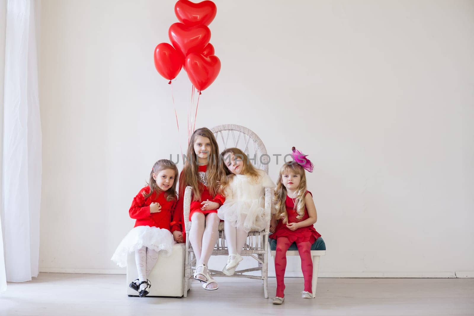 Kids with red balloons for birthday in the interior of the white room