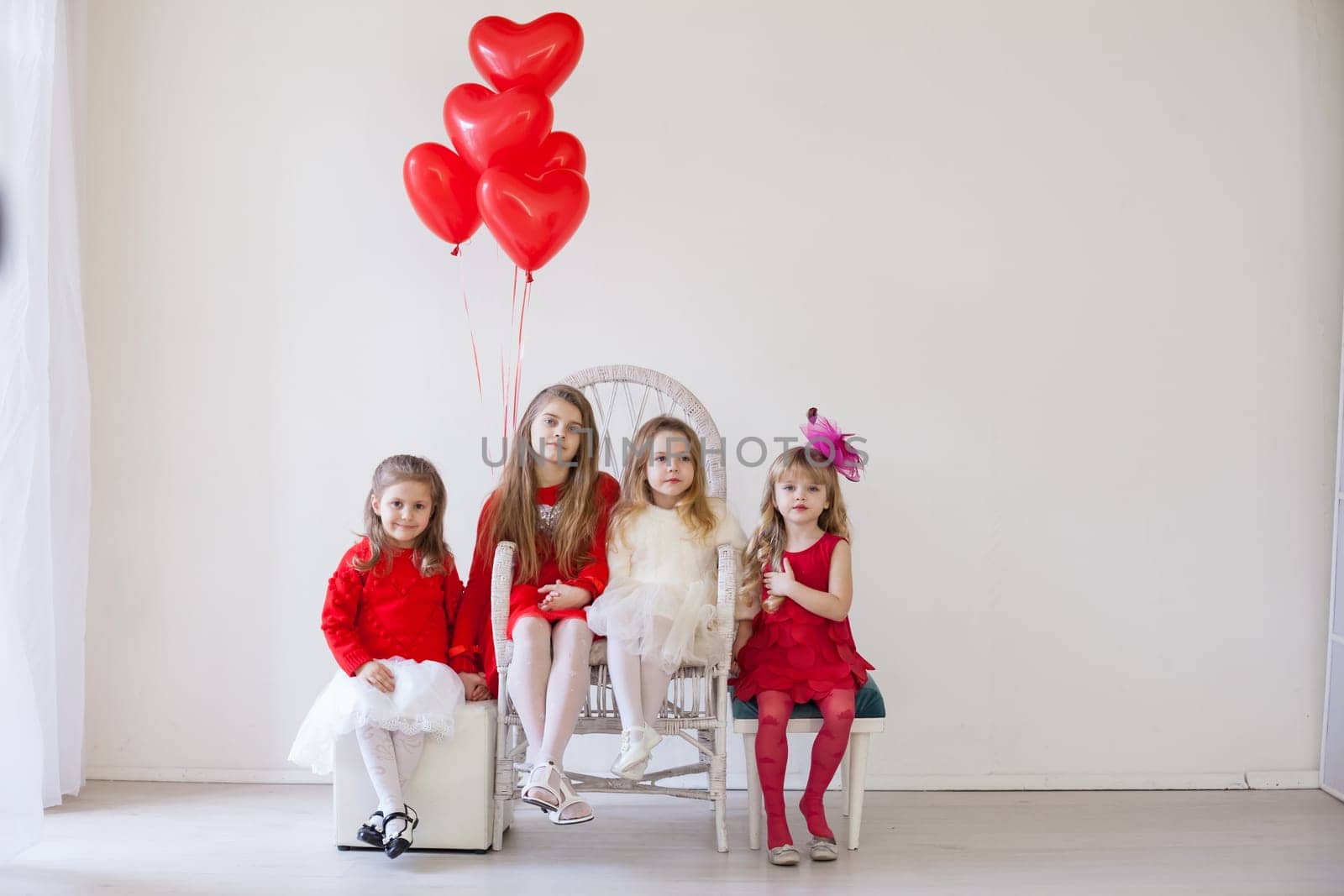 Kids with red balloons for birthday in the interior of the white room