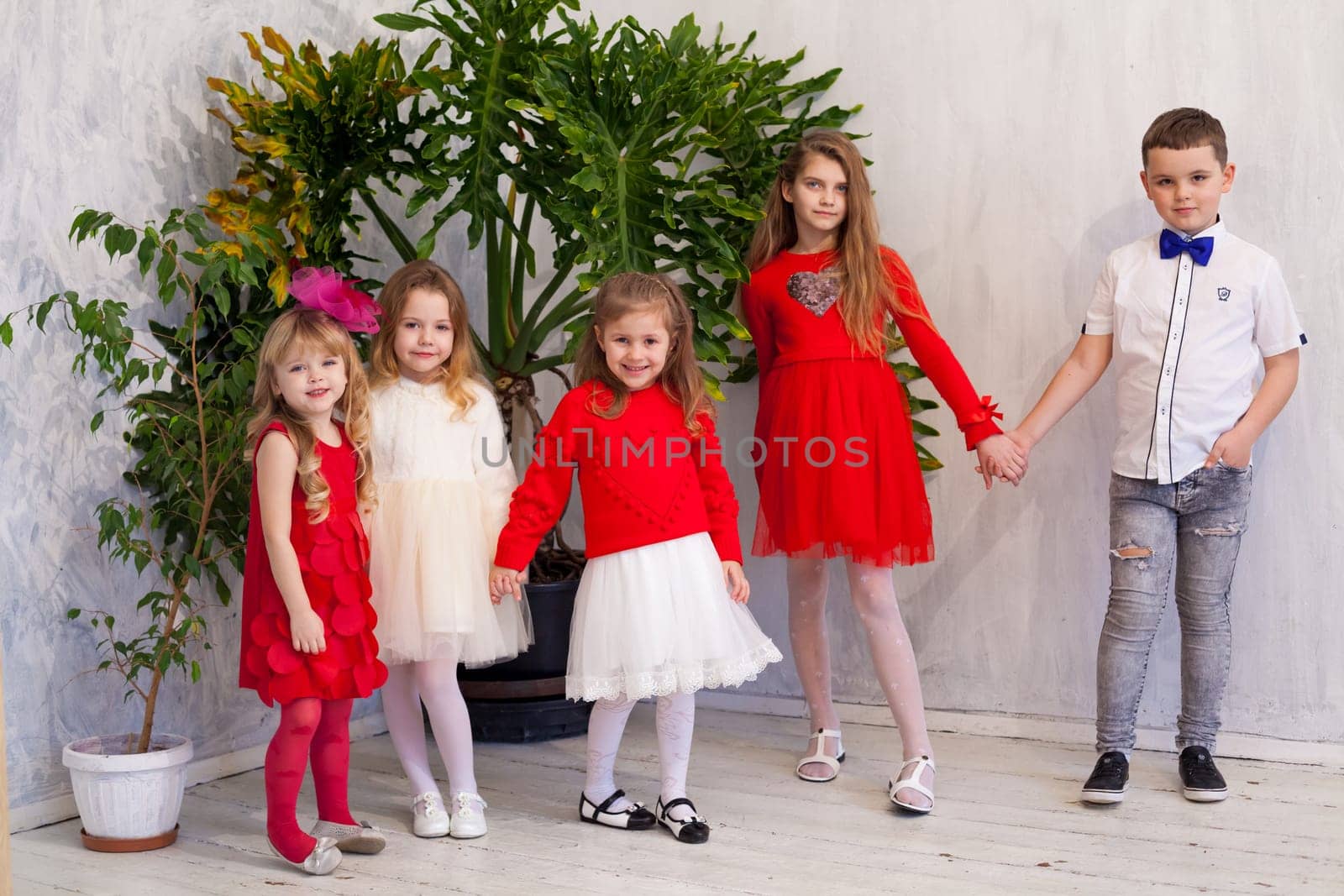 Kids friends for a birthday in the interior of the white room by Simakov