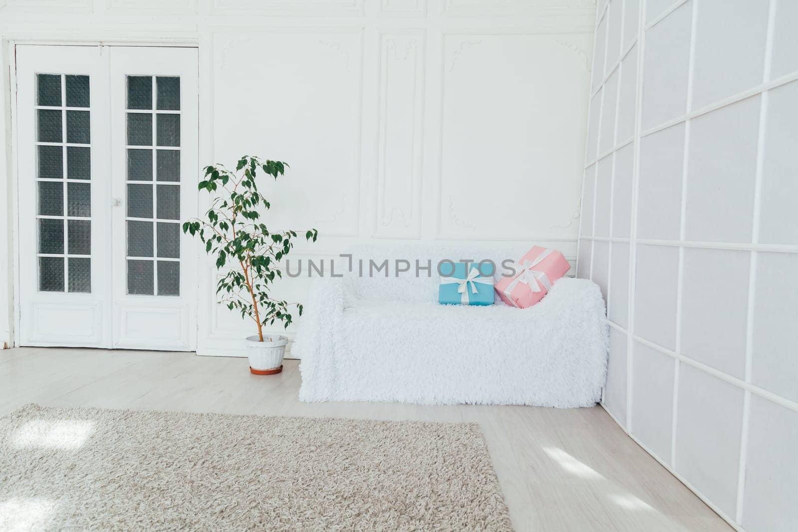 white vintage sofa with a gift in the interior of an empty white room by Simakov