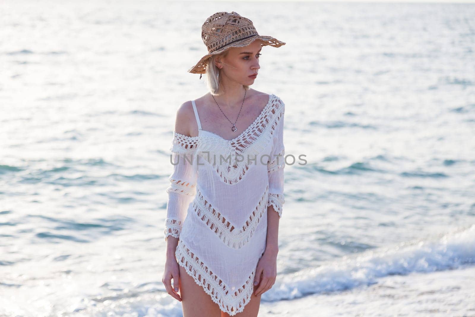 portrait of a woman in a dress and hat on the beach of the sea