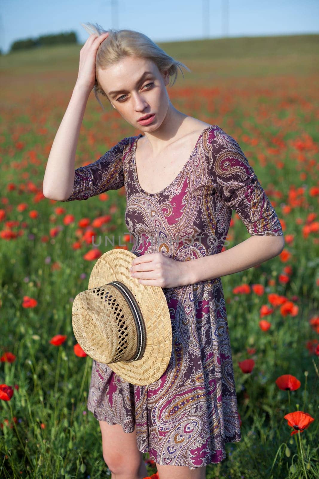 portrait of a woman in a dress in a field of red poppies