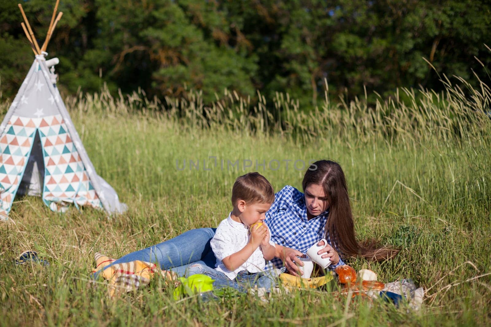 Mom and son eat on a picnic in the woods