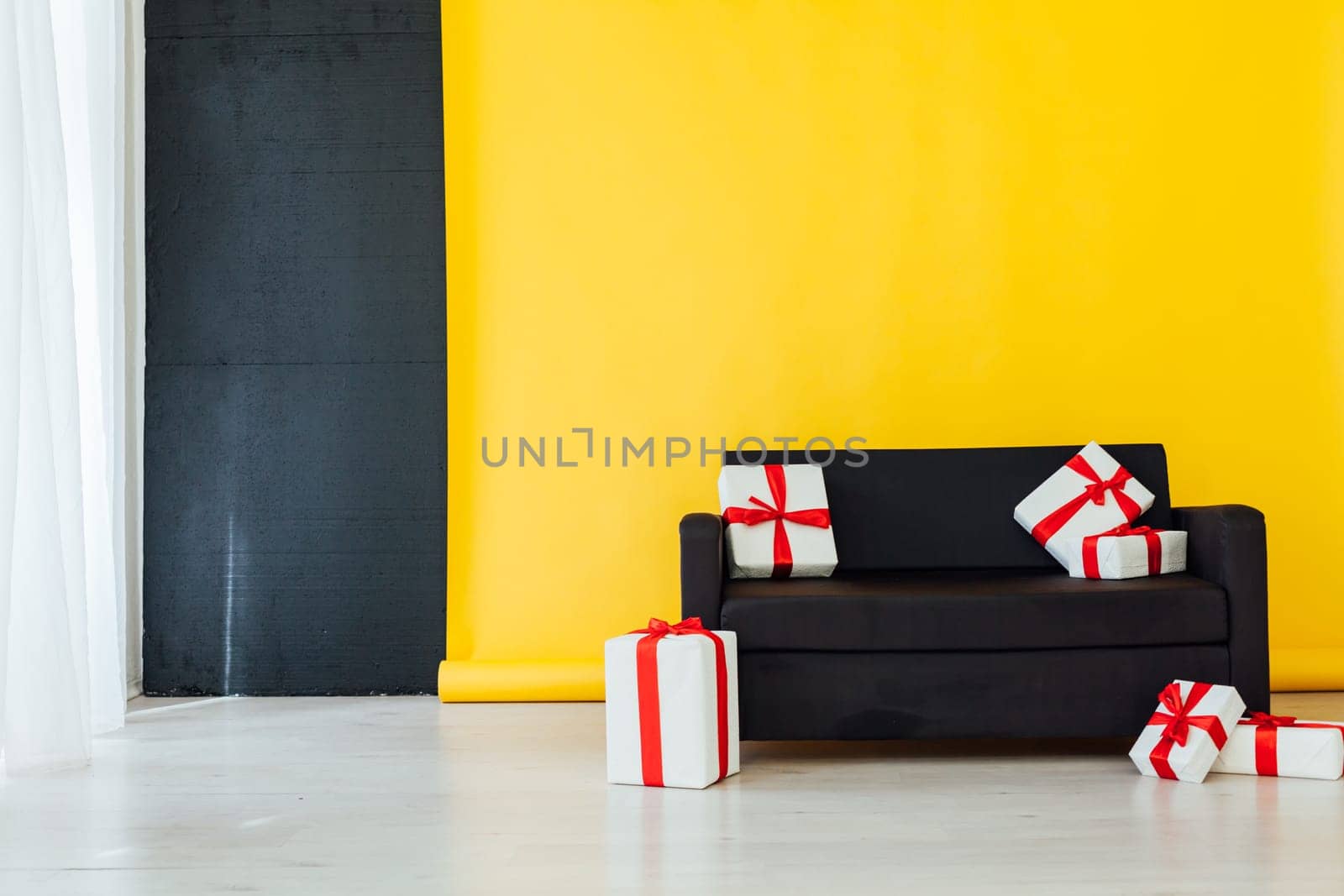 black sofa with gifts in the interior of the room with a yellow background