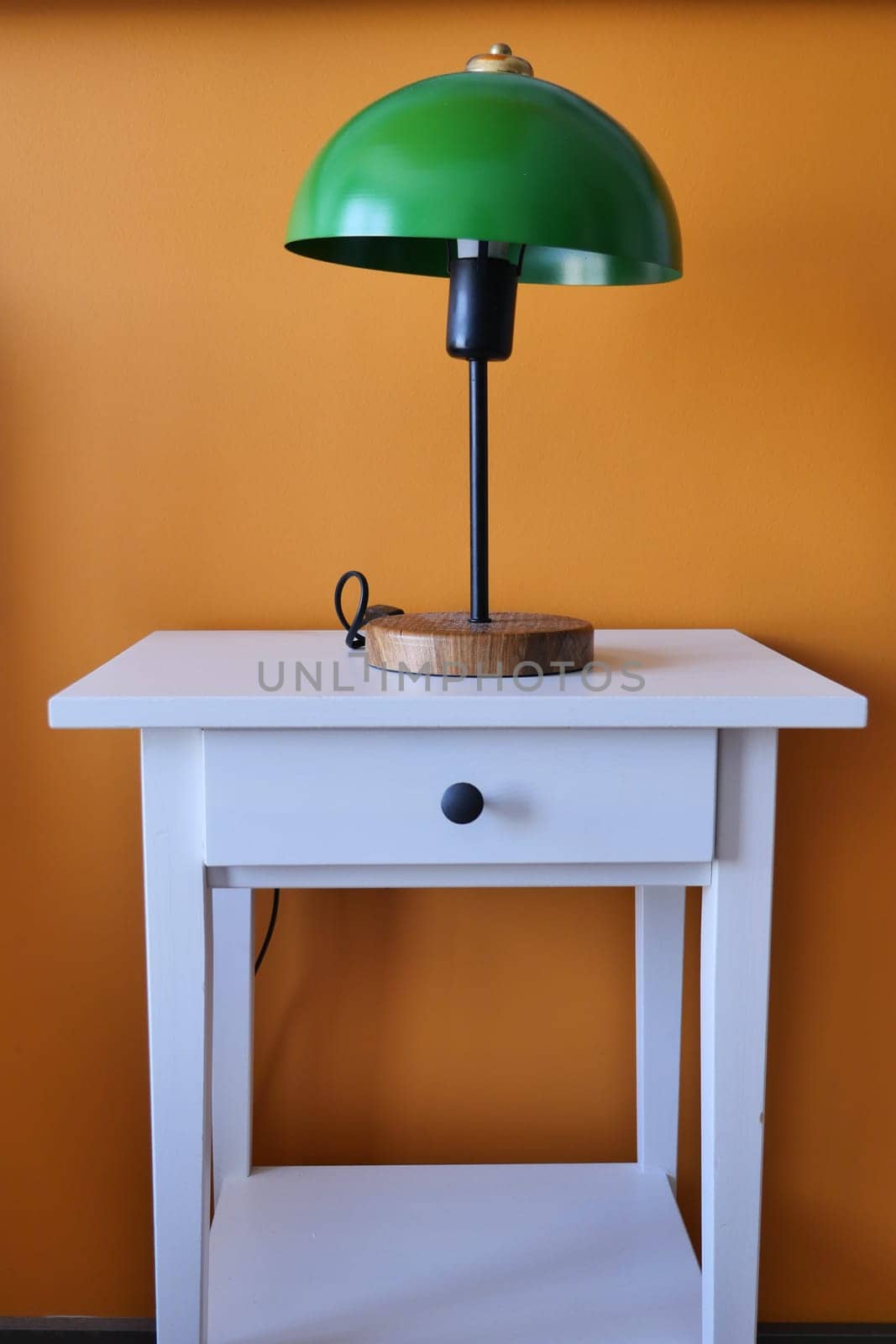 table lamp against orange color wall in bed room .